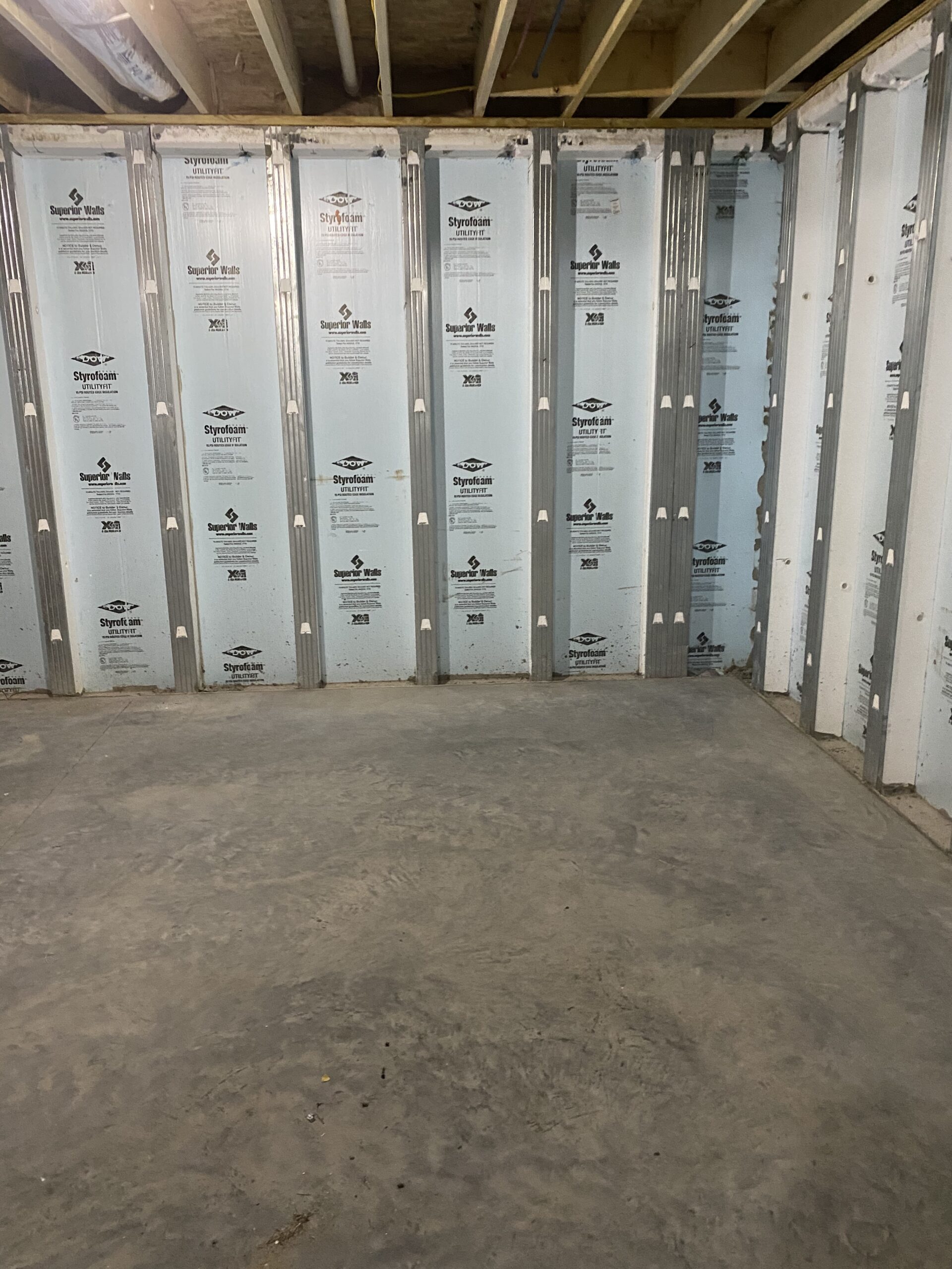 nfinished basement with exposed insulation and untreated concrete floor.
