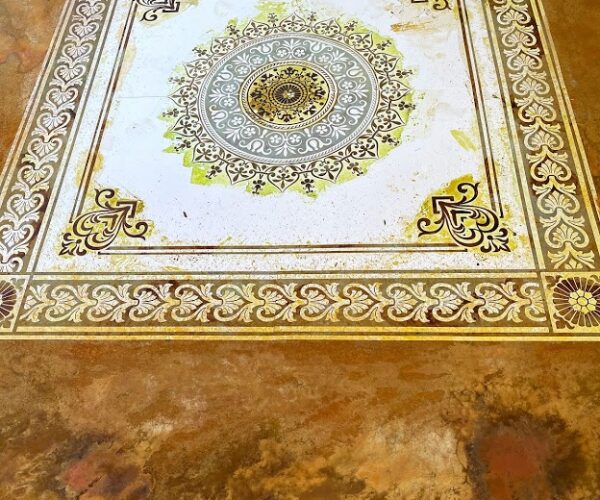 Stencil still on the floor with different colored acid stains applied over it