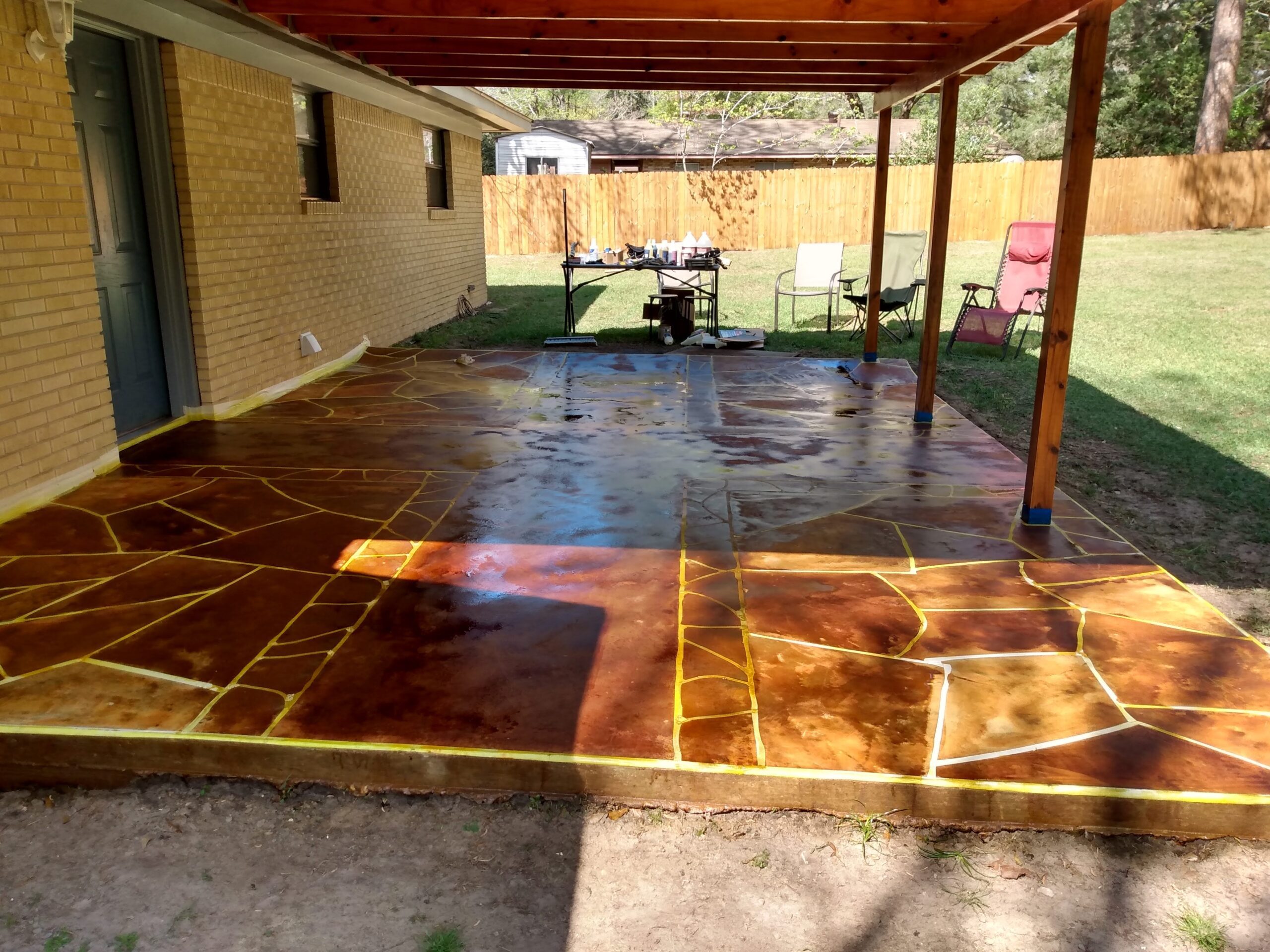 Photo capturing the porch floor after the application of different colored acid stains, showing the beginning of the faux flagstone transformation