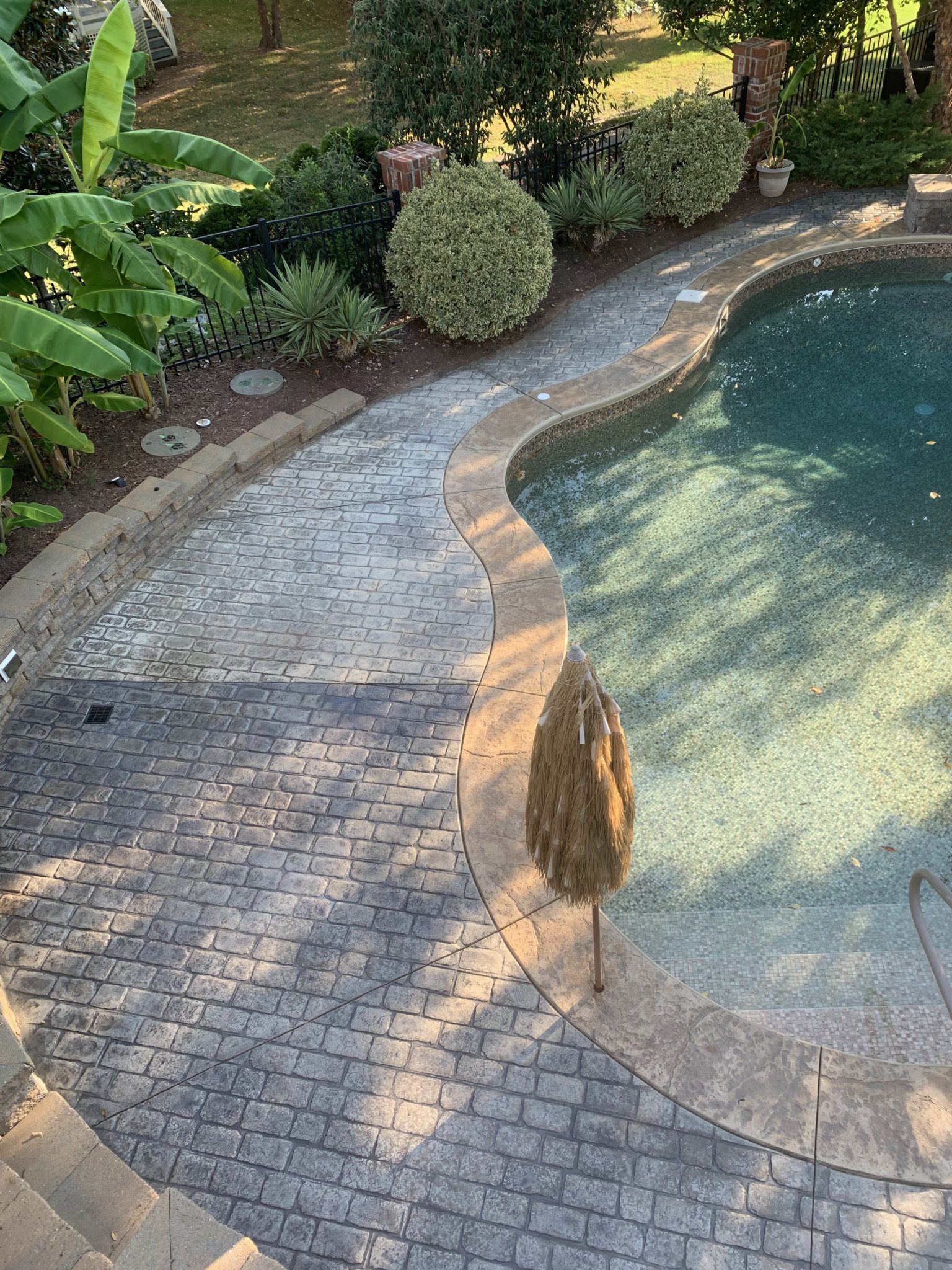 Midway photo depicting half of the pool deck revitalized with Charcoal stain and the remaining half in its pre-stain condition