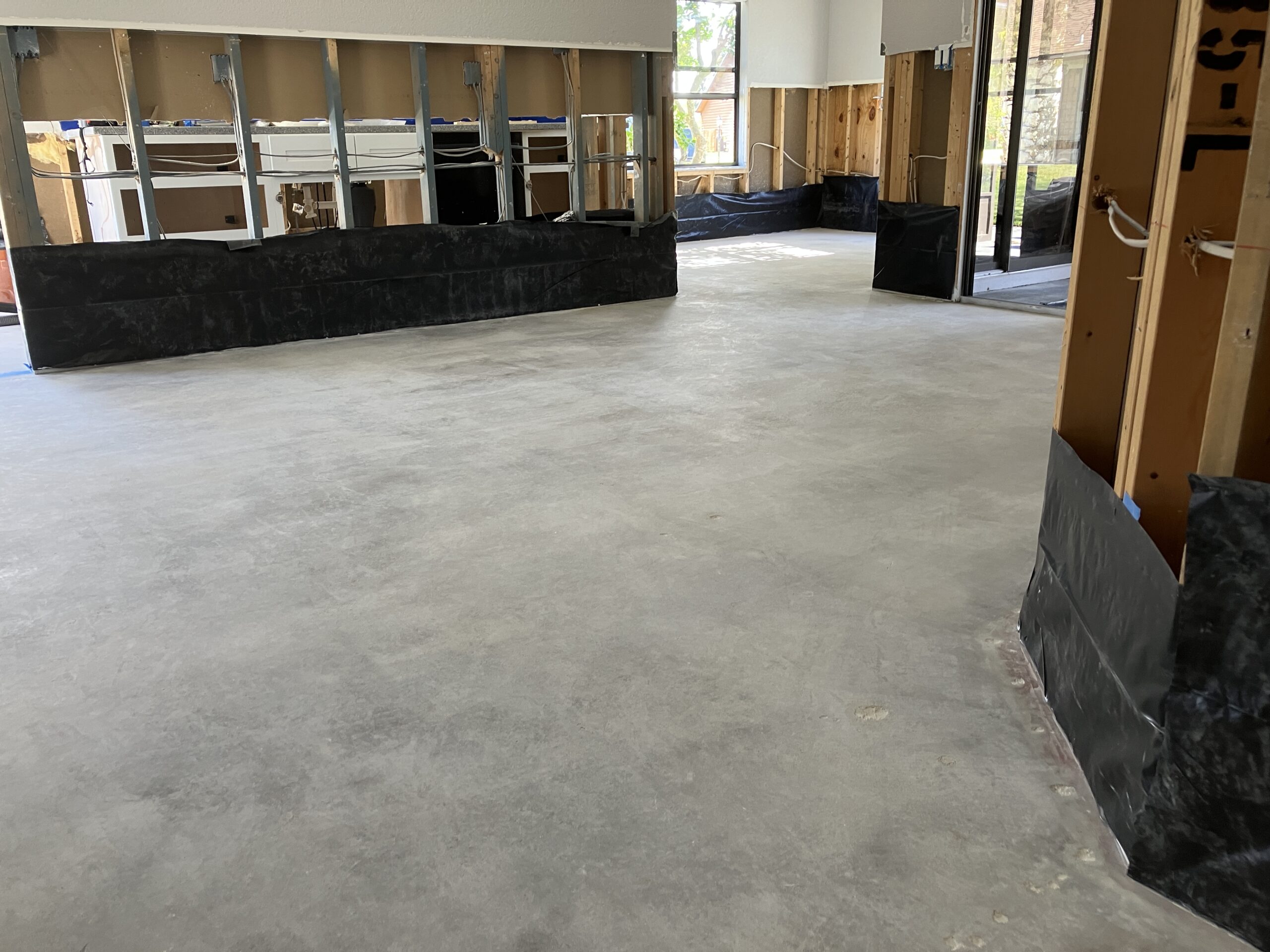 Image of a flood-damaged home interior with removed carpet and plank flooring, revealing a bare, untreated concrete floor.