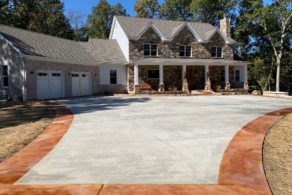 A concrete driveway with edging stained by Cola EverStain™, matching the earthy tones of the estate home