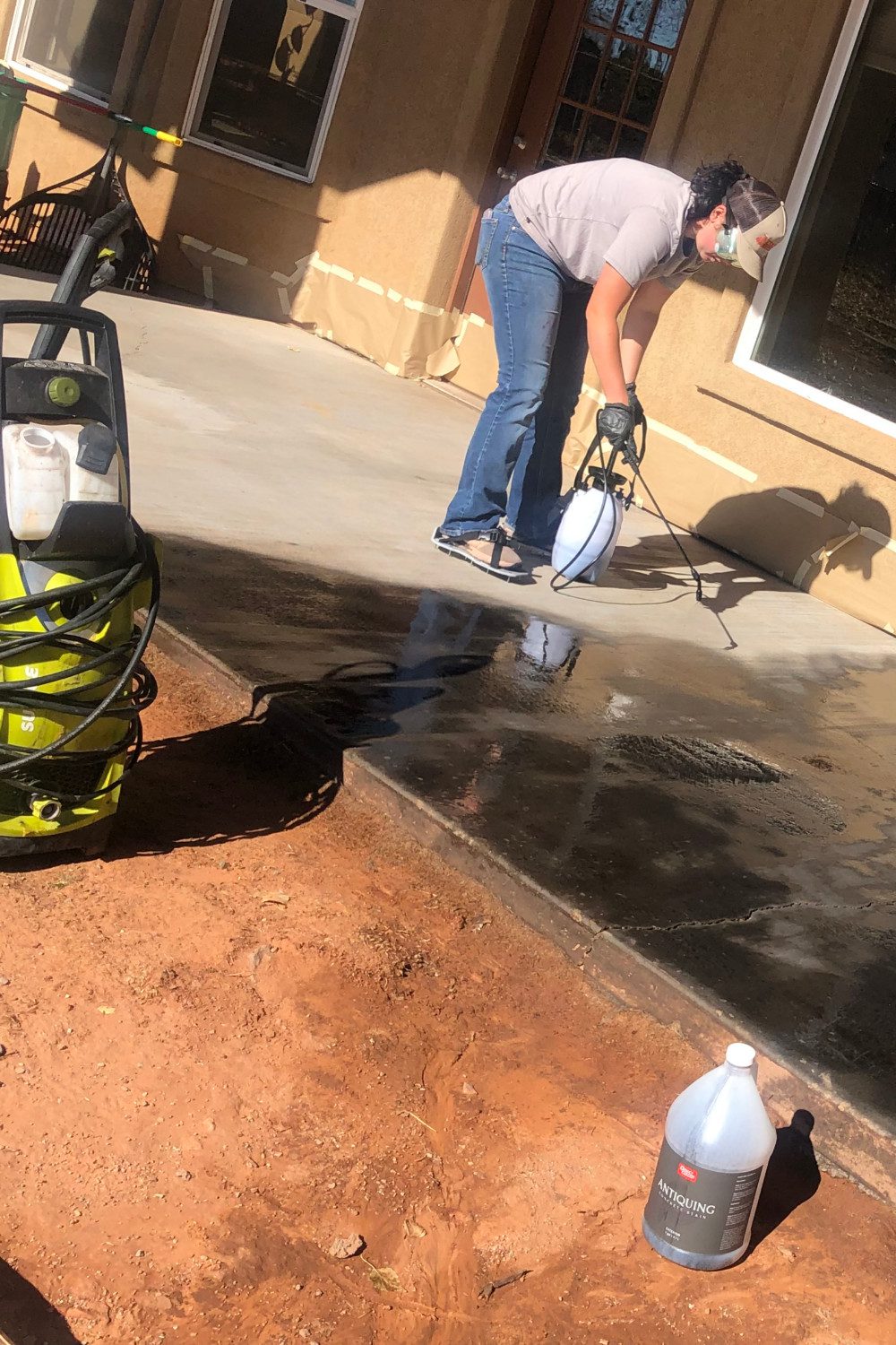 Woman spraying concrete stain from a far corner to maintain a clear path to exit