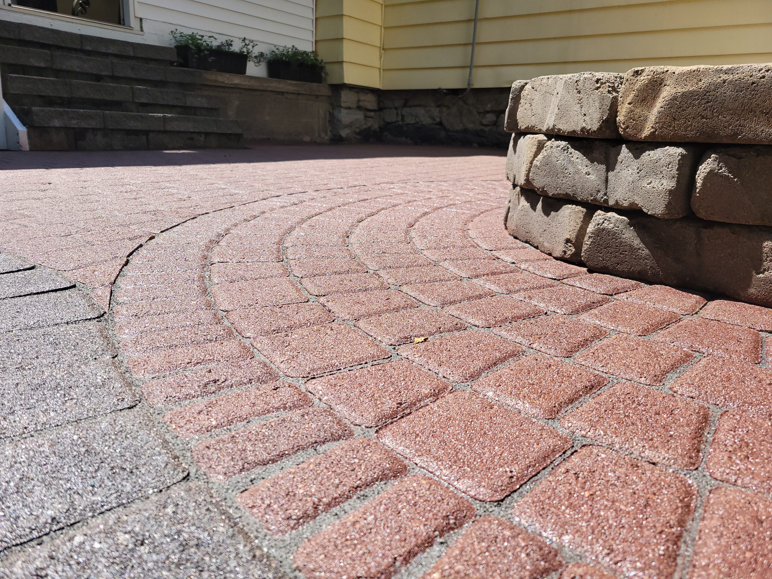 Close-up view of the patio pavers showcasing the rich texture and color of Cinnabar tint and grey polymeric sand.