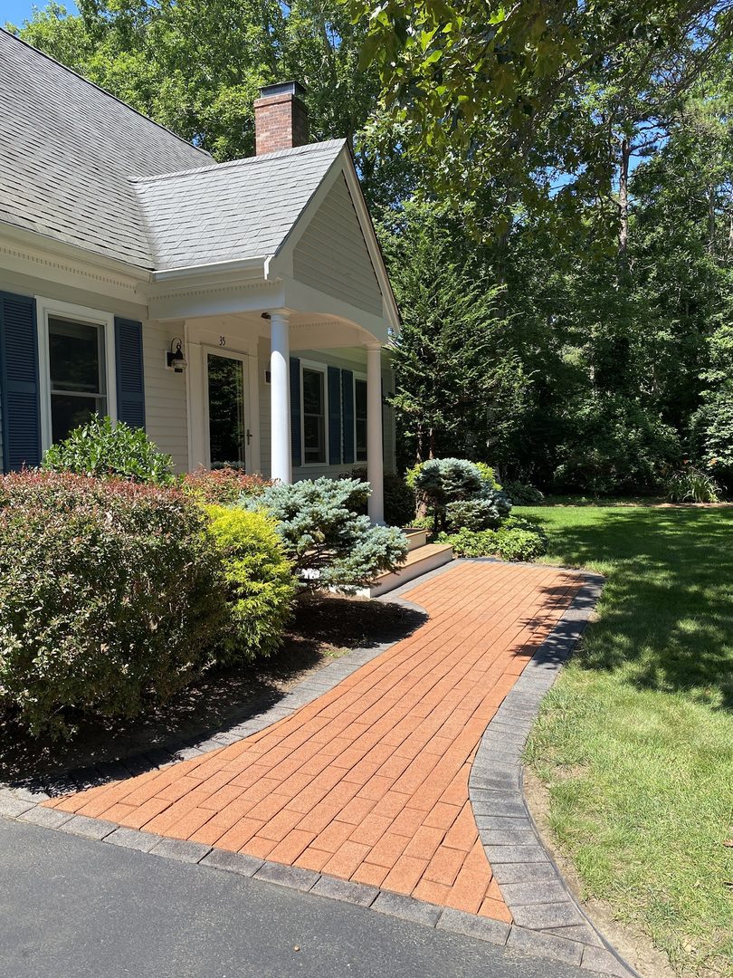 A stunning terracotta Portico stained paver walkway with a warm, earthy hue, featuring an outer edge stained with charcoal Portico paver stain.