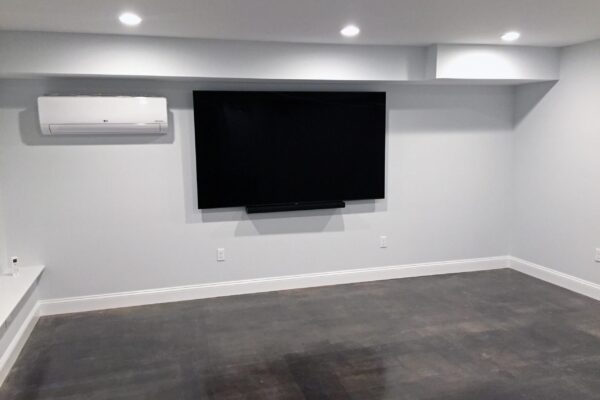 Renovated basement room with a TV, showcasing the gleaming floor finish
