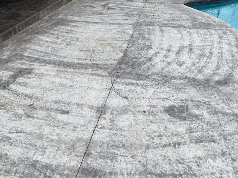 Damaged dark charcoal stamped concrete before restoration