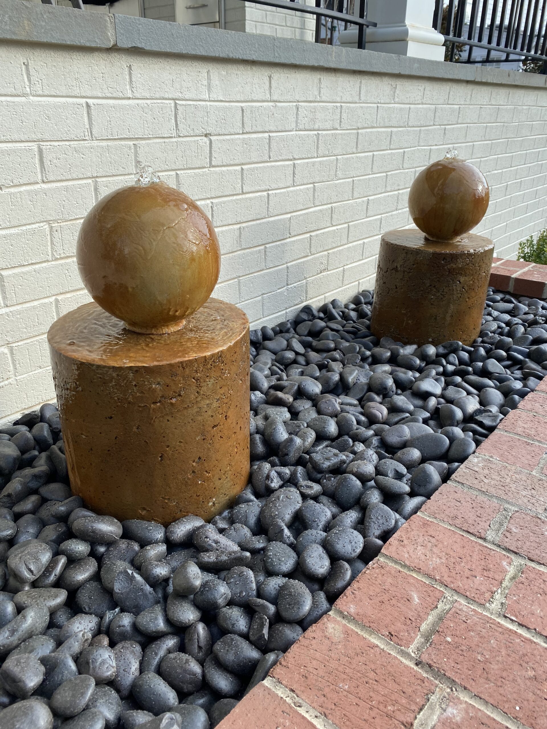 The completed DIY concrete fountain, beautifully stained with EverStain's Malayan Buff and Desert Amber, standing as a vibrant centerpiece against the patio's brick background