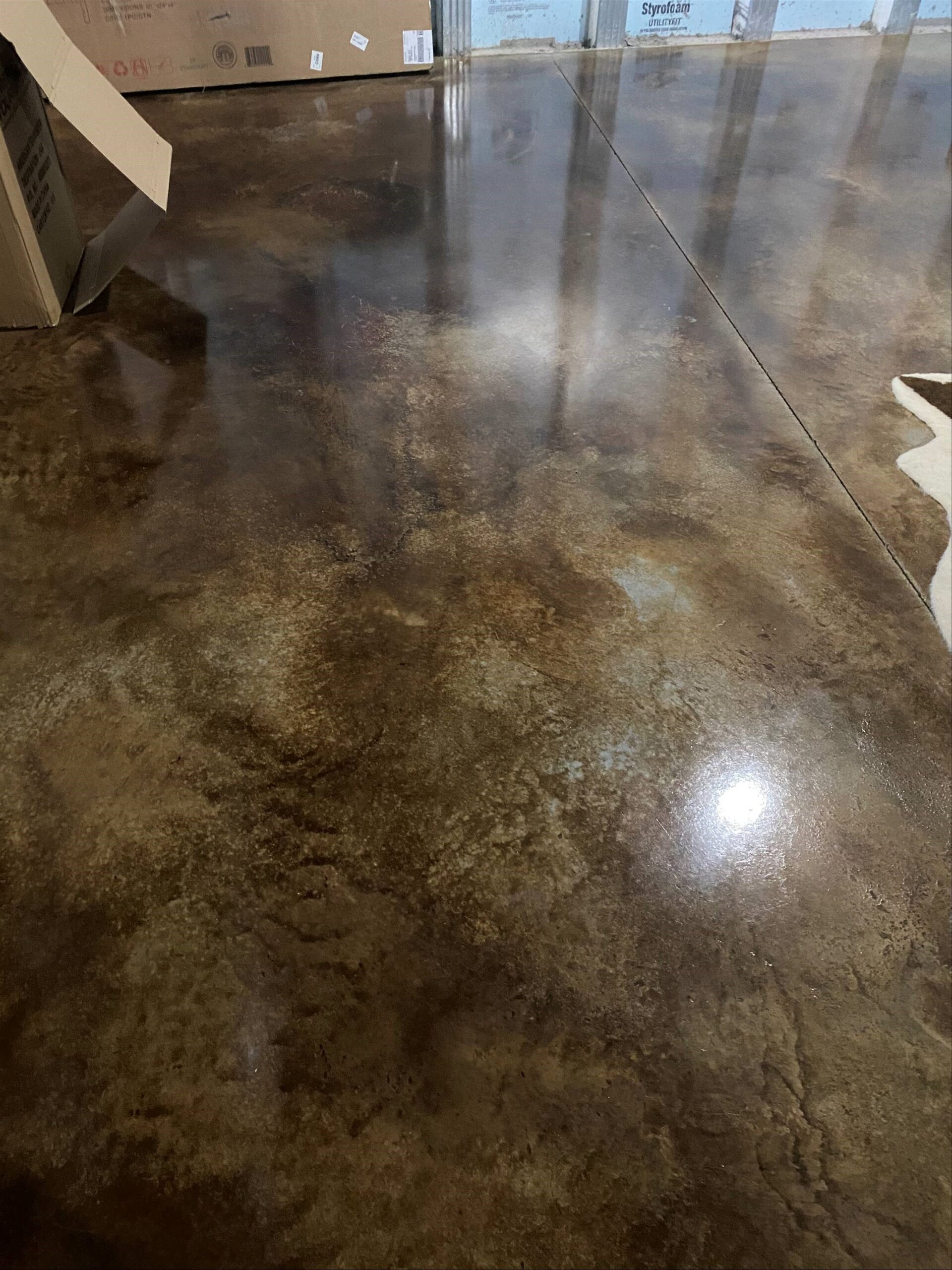 A stunning finished project featuring a waxed Coffee Brown & Desert Amber acid-stained concrete basement floor, showcasing a beautiful and durable surface.