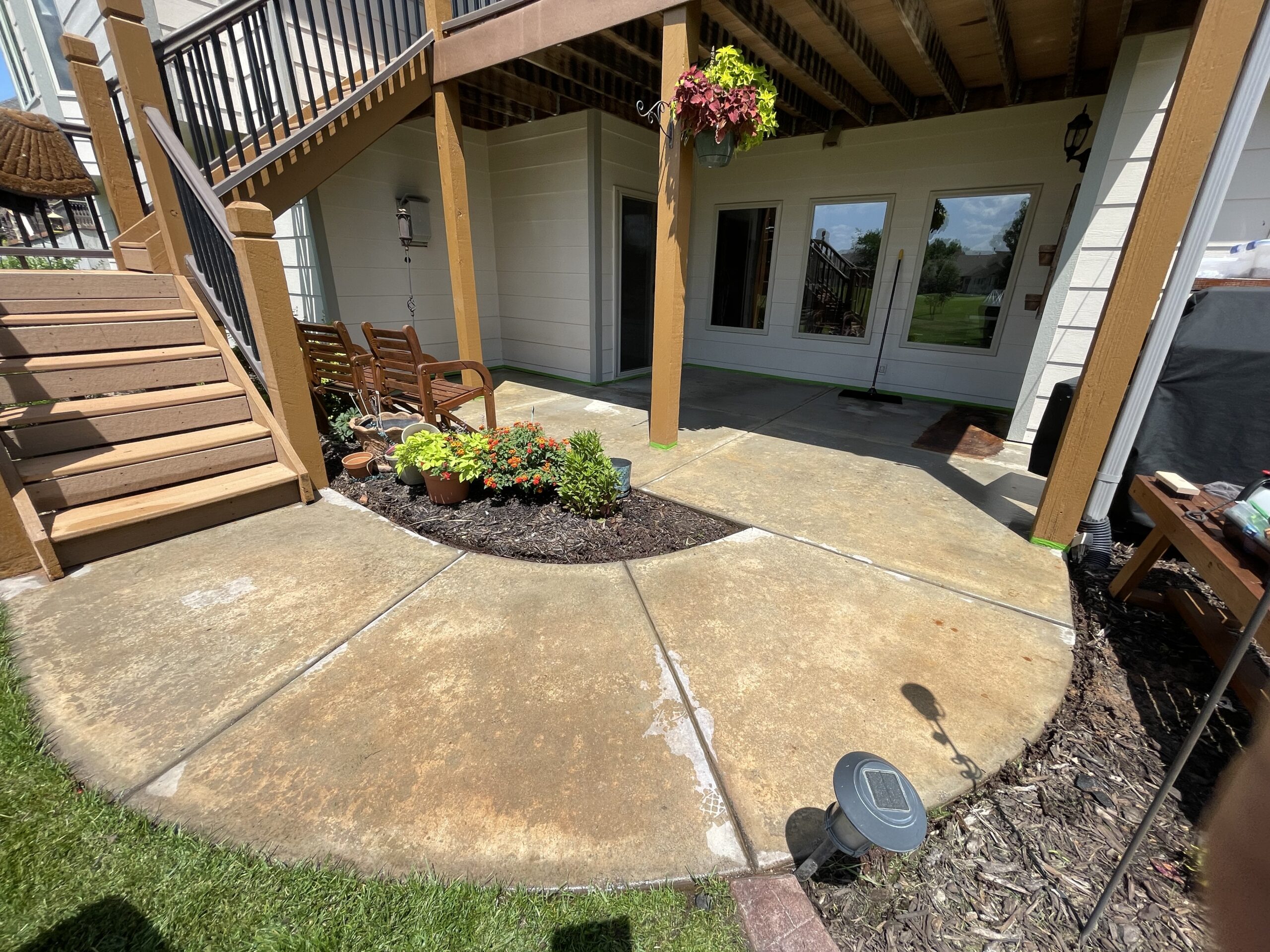 Round patio before application, showing dull concrete surface
