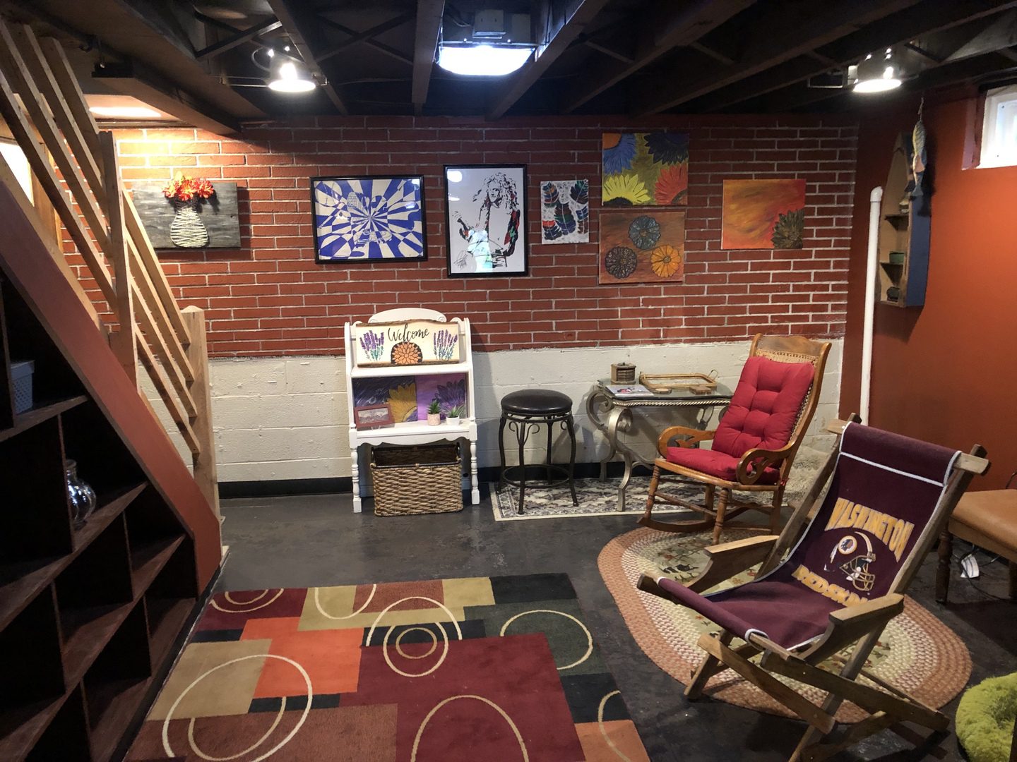 Cozy basement living space with two chairs, artfully decorated with paintings on the walls