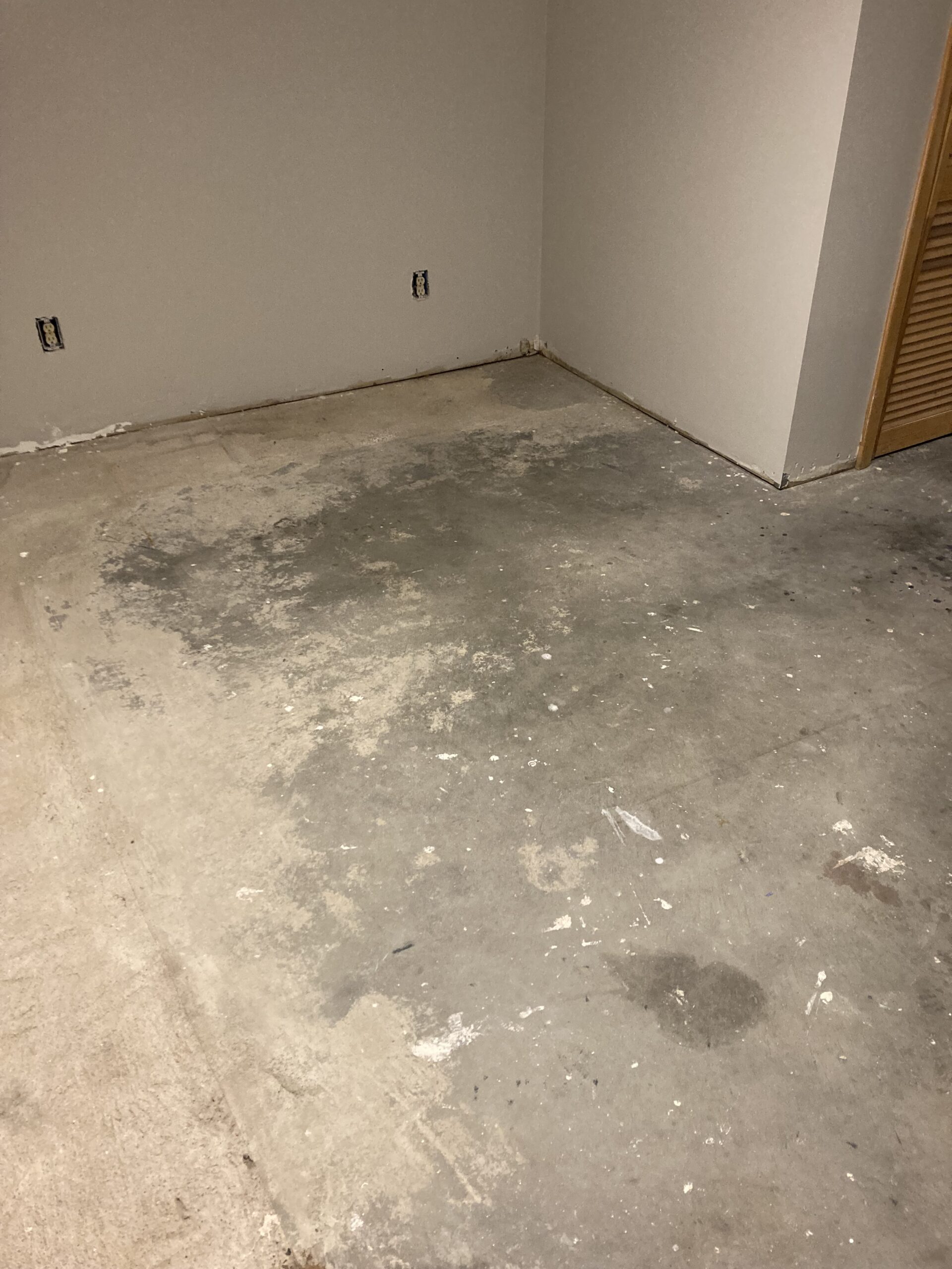 Poorly maintained basement floor, covered in paint drips and stains