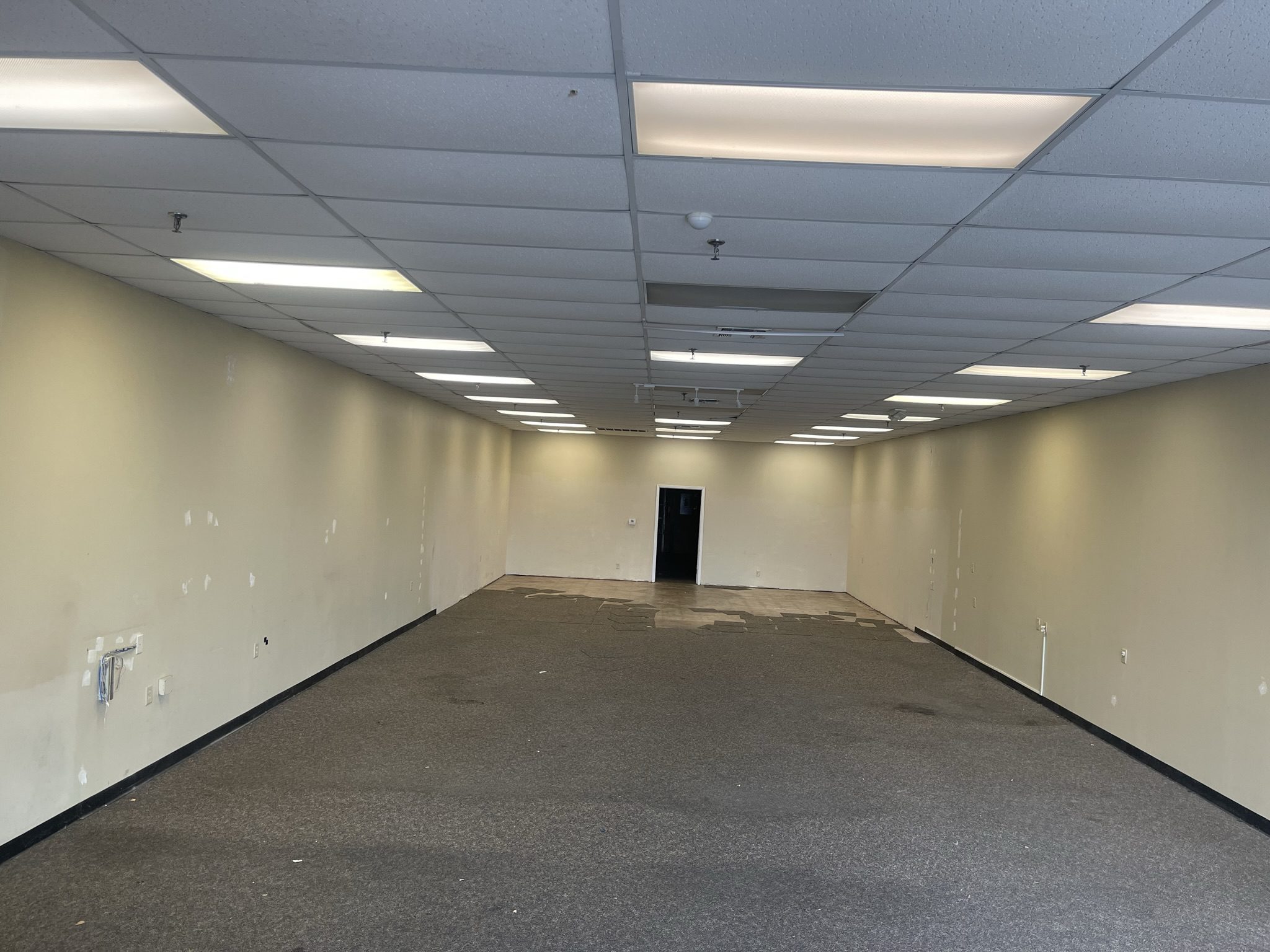 Image of the original interior space, covered in adhesive carpet tiles prior to renovation