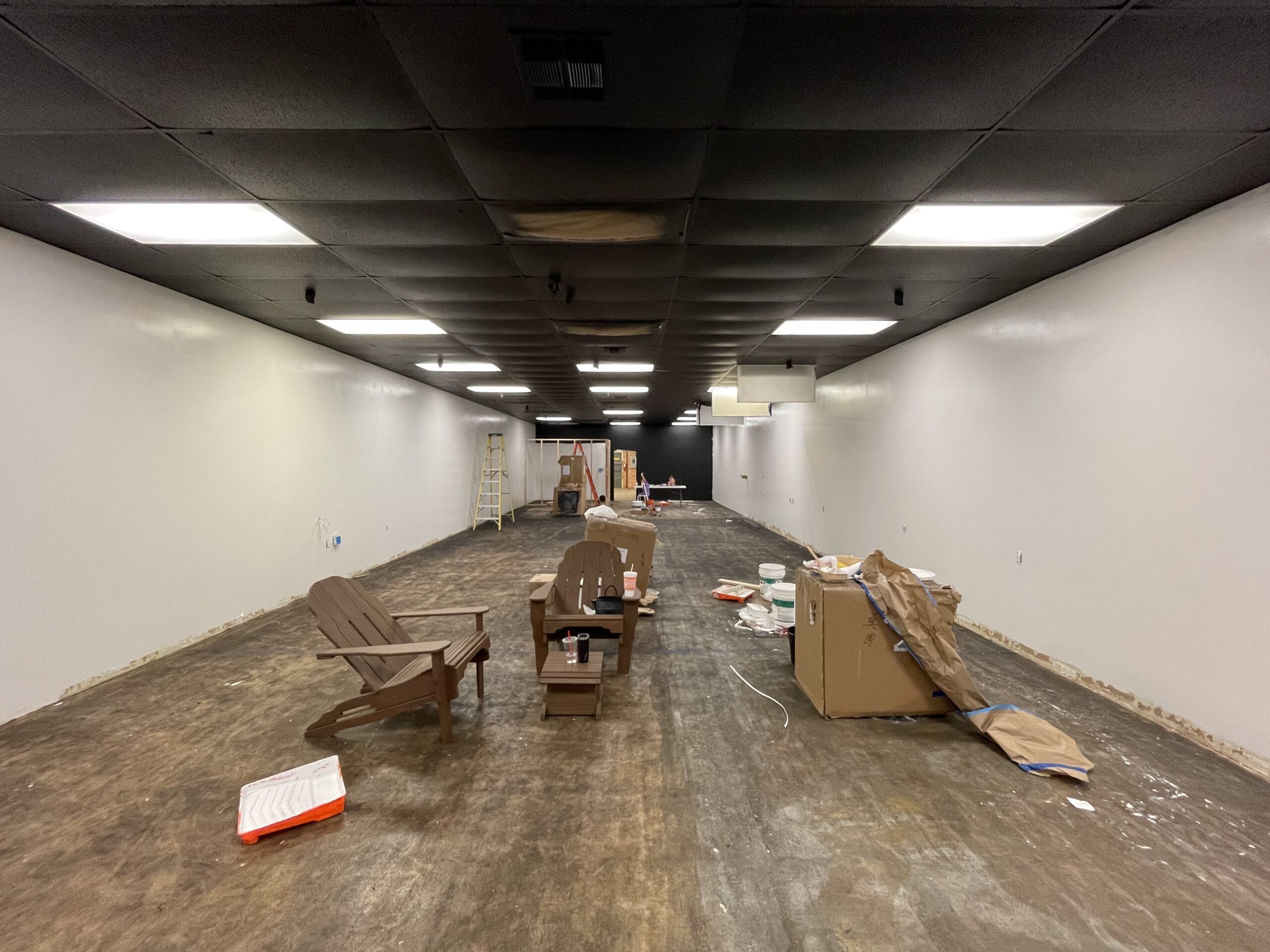 Image showing the floor covered in mastic after removing carpet tiles, along with paint splatters from the freshly painted black ceiling and white walls
