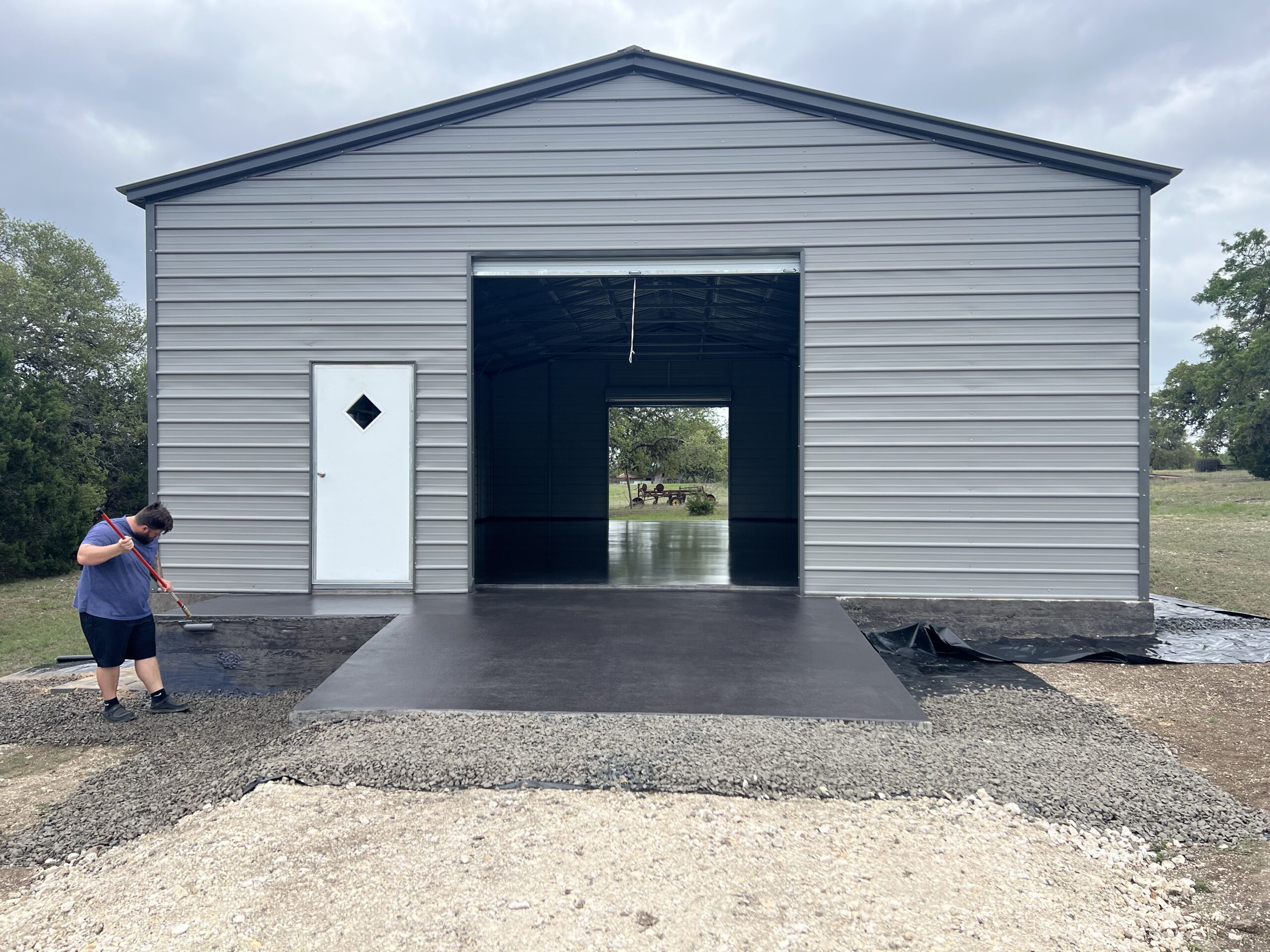 DIYer in action, rolling Charcoal AcquaTint™ onto the new concrete floor after spraying