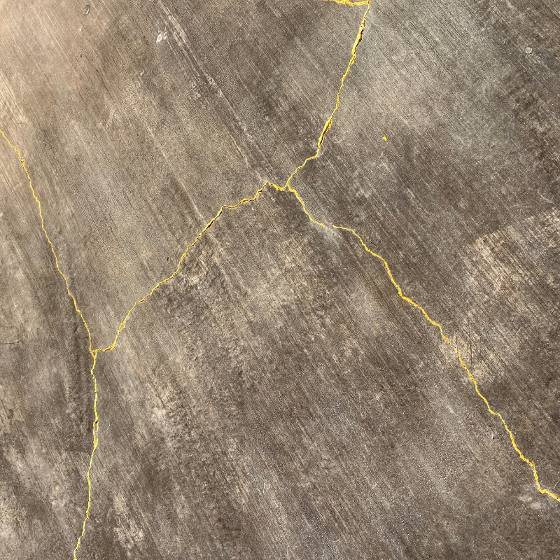 Detail of gold acrylic craft paint on concrete cracks for a patio
