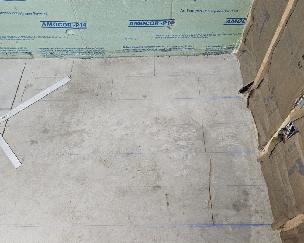 A chalk line being used to map out the future tile design on the concrete floor