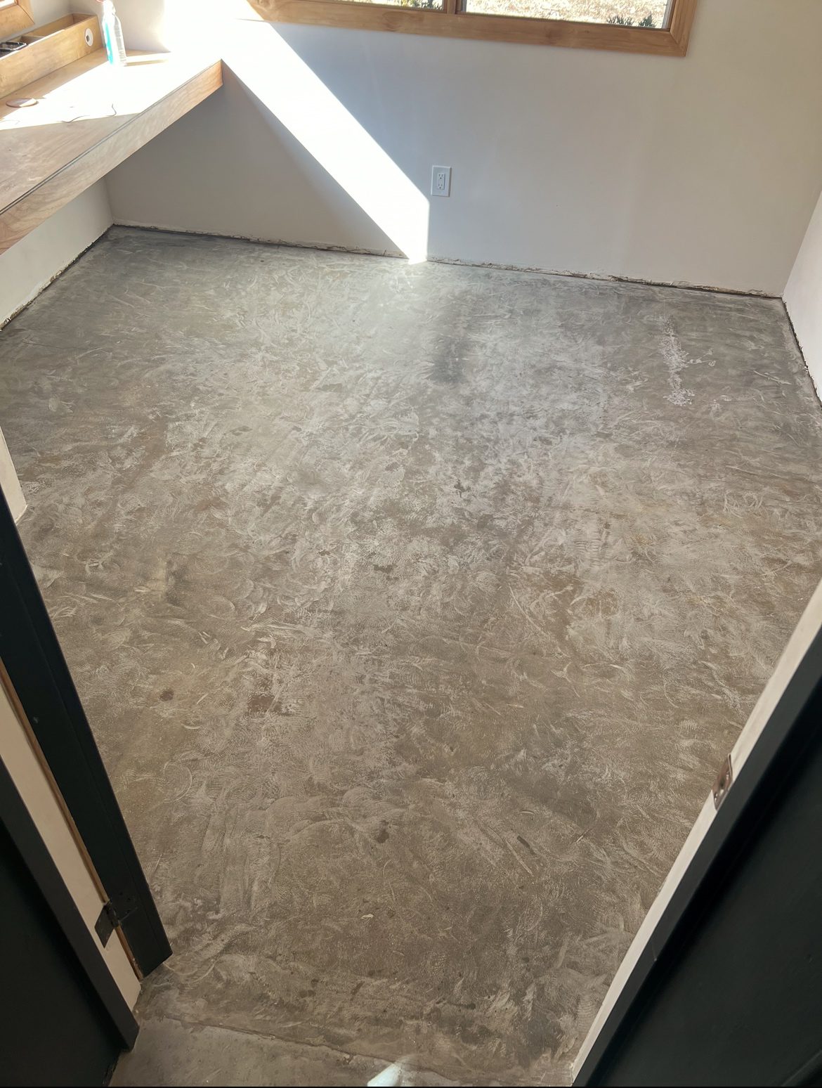 DIYer grinding the concrete floor with an angle grinder and diamond pad and filling cracks with a concrete patching compound