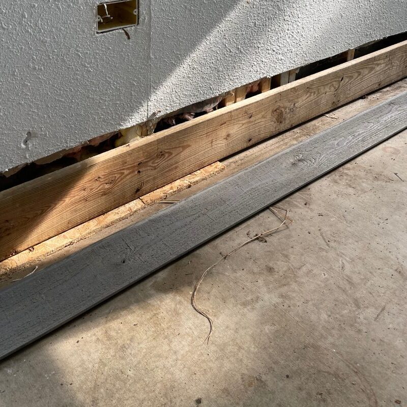 Pre-transformation sunroom floor with evident wear and tear, including stains from dirt, rust, paint, and drywall mud