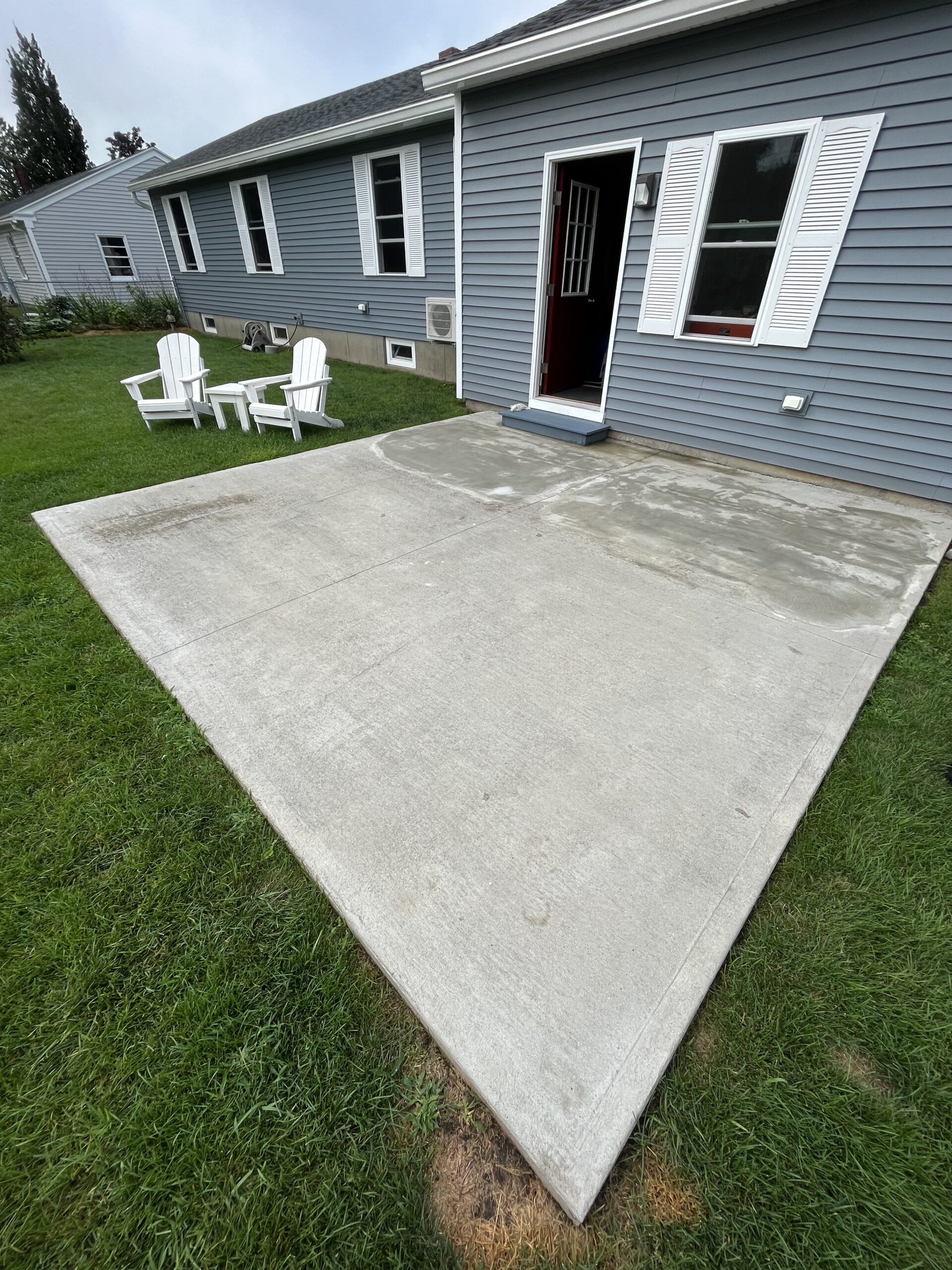 A cracked patio surface with a cement repair visible across it before black everstain acid stain