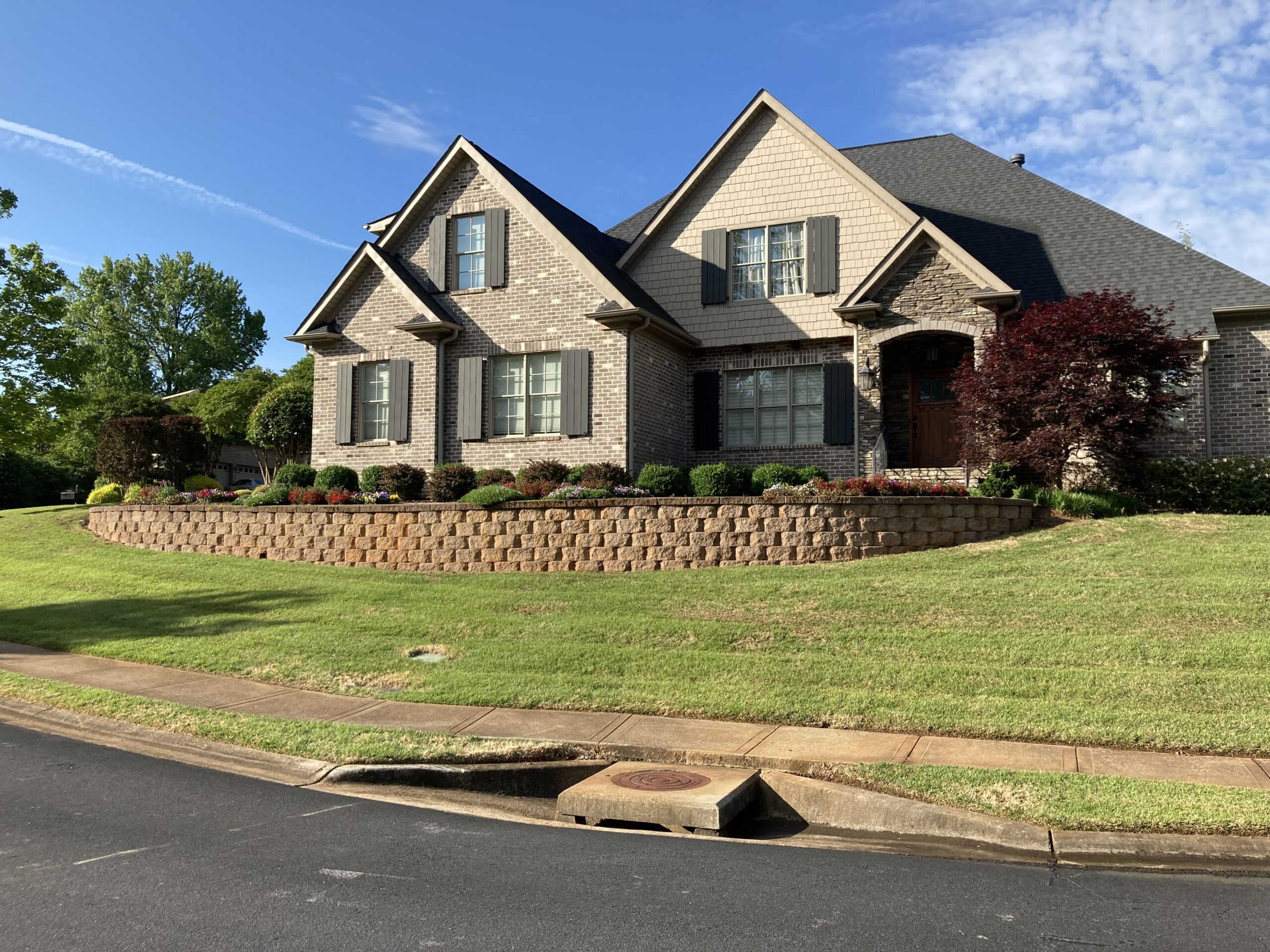 A blotchy buff-colored retaining wall with visible mold/mildew marks and red clay stains