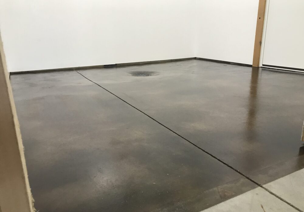 The renovated mechanical room with a black acid-stained floor exhibiting brown hues, sealed with a satin finish AcquaSeal