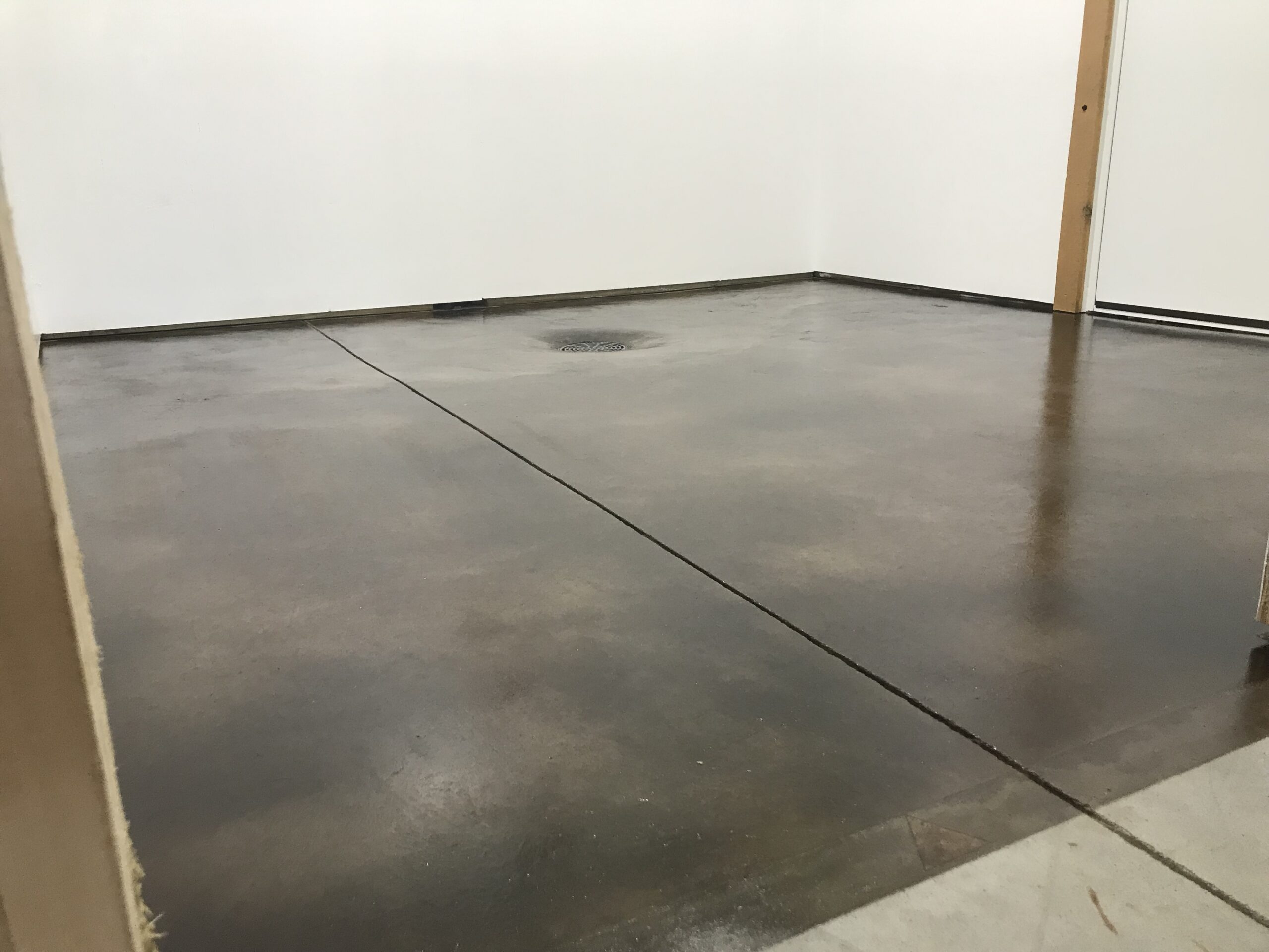 The renovated mechanical room with a black acid-stained floor exhibiting brown hues, sealed with a satin finish