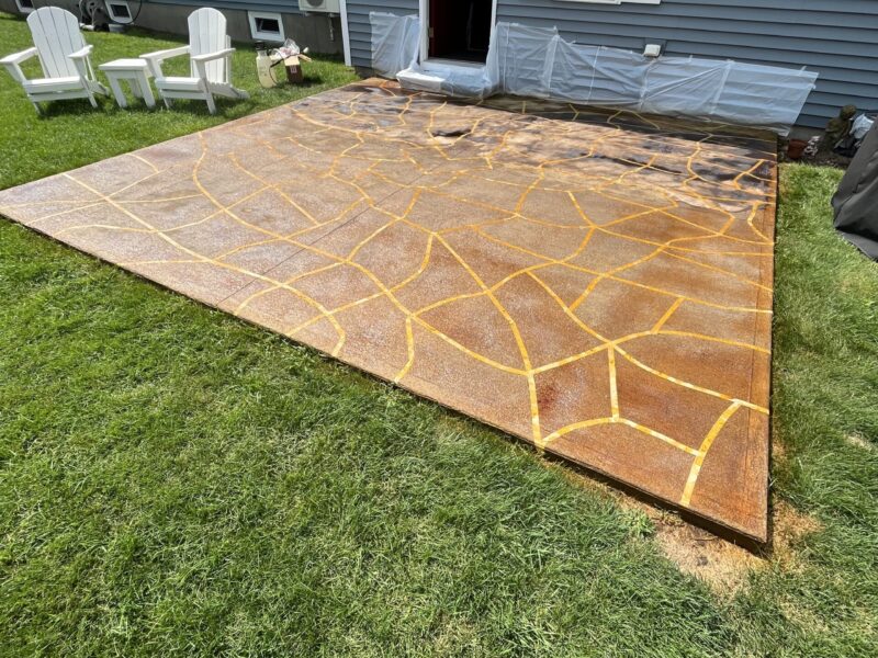 The taped concrete patio floor immediately after being sprayed with Black EverStain acid stain.