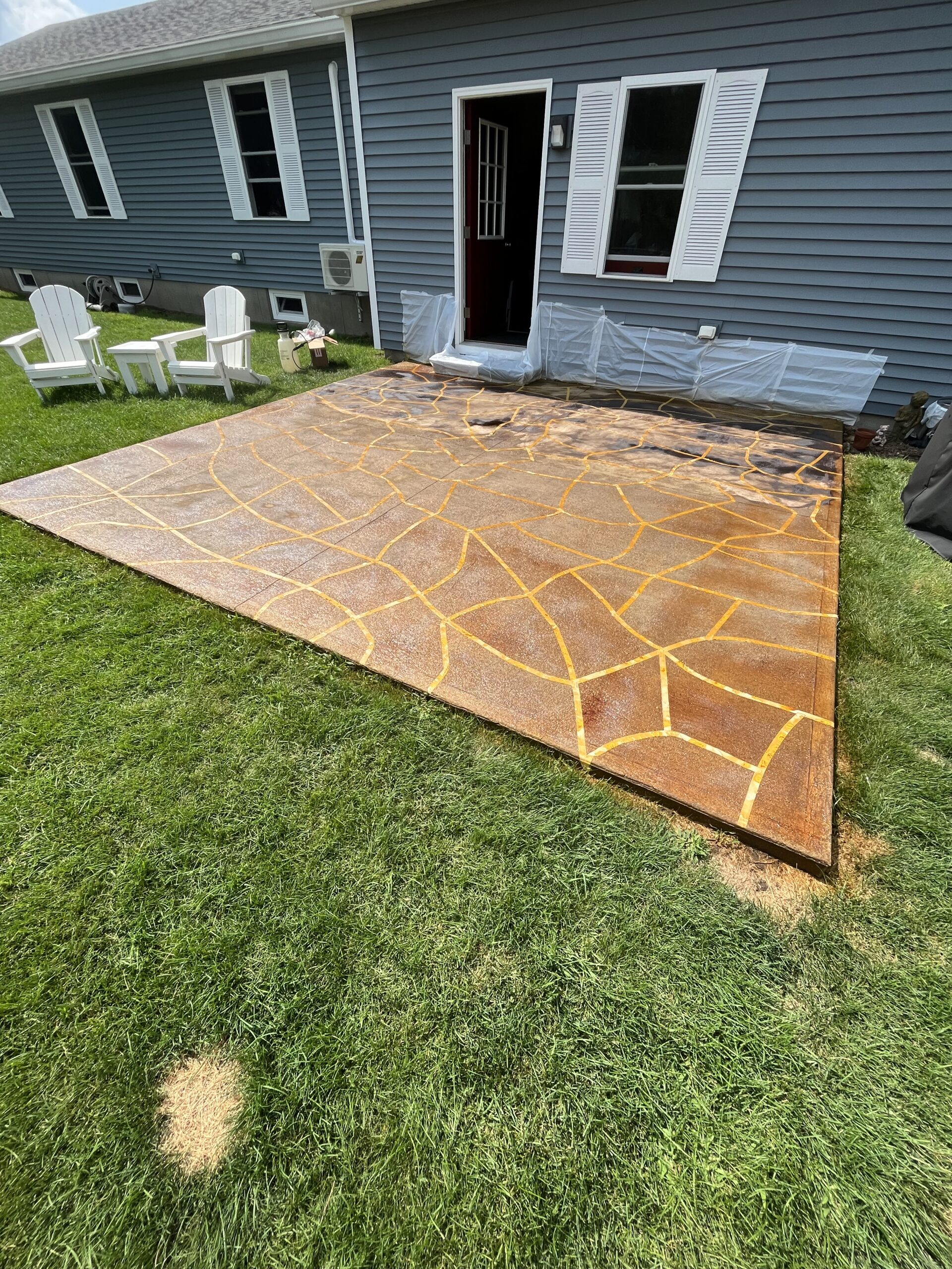 The taped concrete patio floor immediately after being sprayed with Black EverStain acid stain.