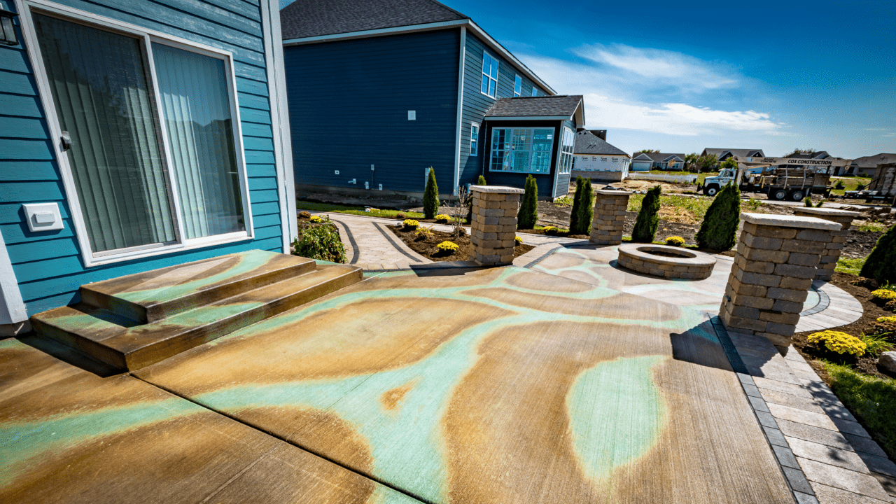 Outdoor concrete patio with swirling patterns created by spraying a mix of azure blue and Miracle Gro, followed by Malayan Buff stain in the spaces between the blue areas.