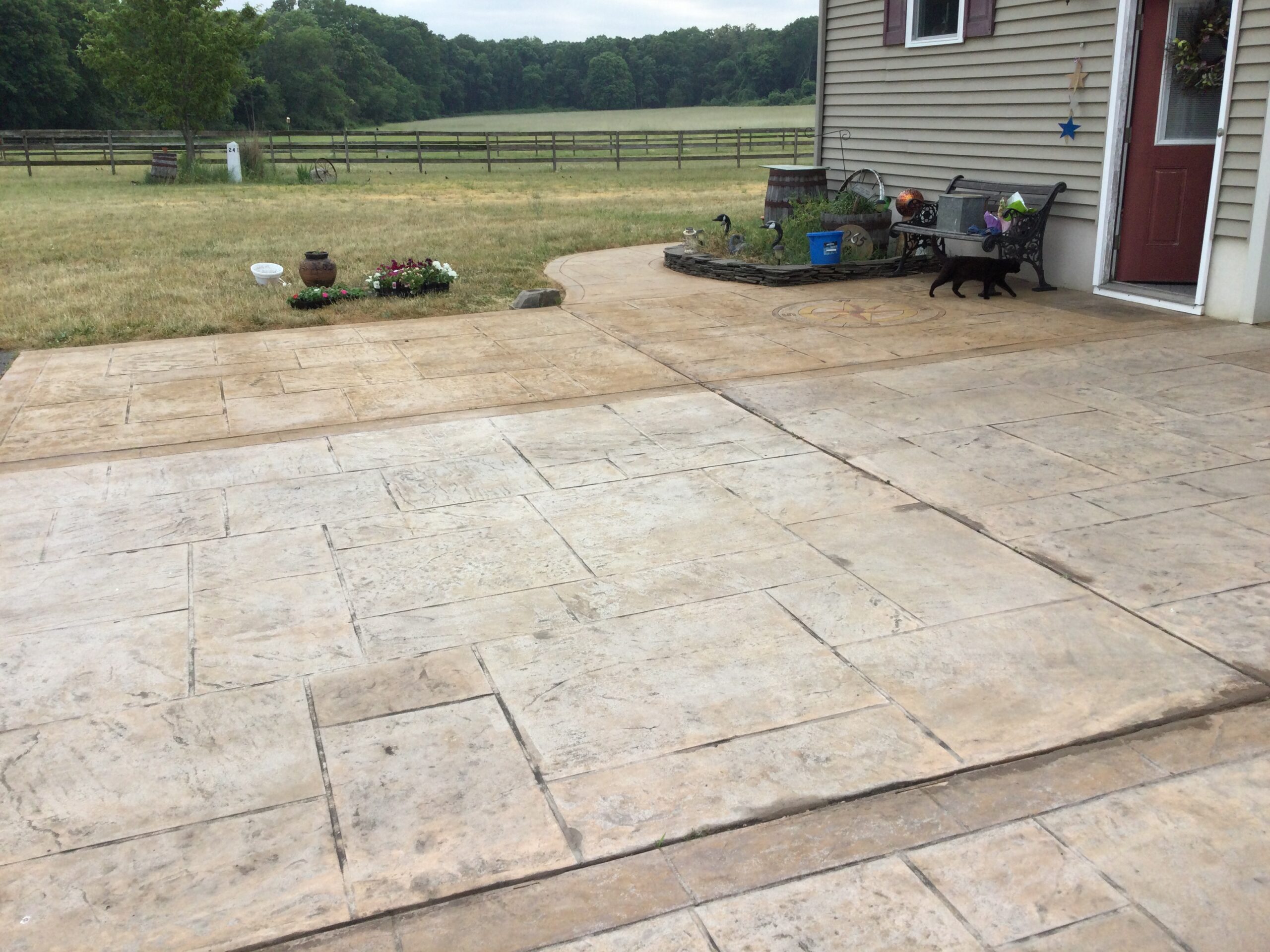 A sun-faded, stamped concrete driveway with a worn-out compass rose imprint