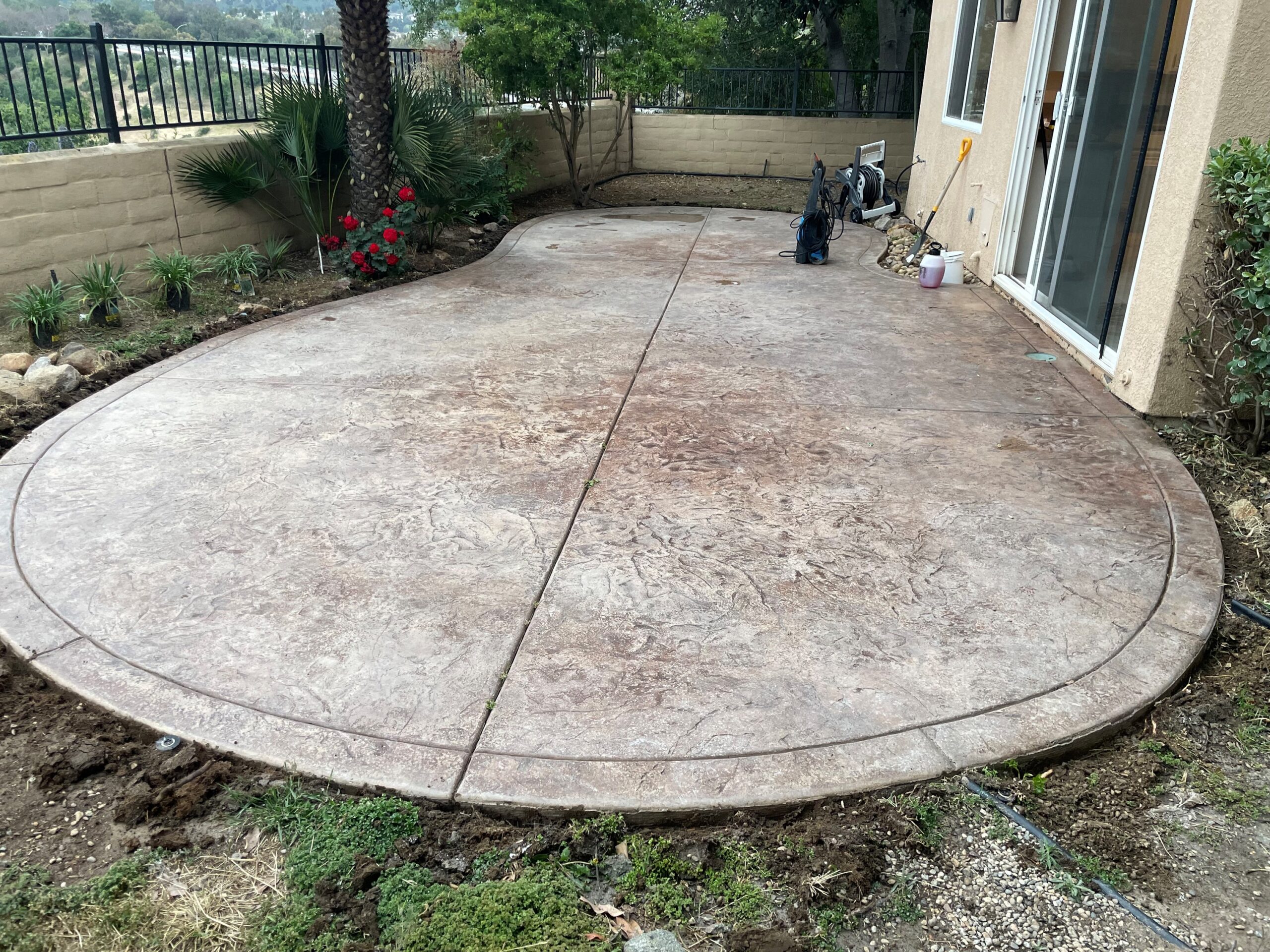 A faded stamped concrete backyard patio, clearly in need of rejuvenation