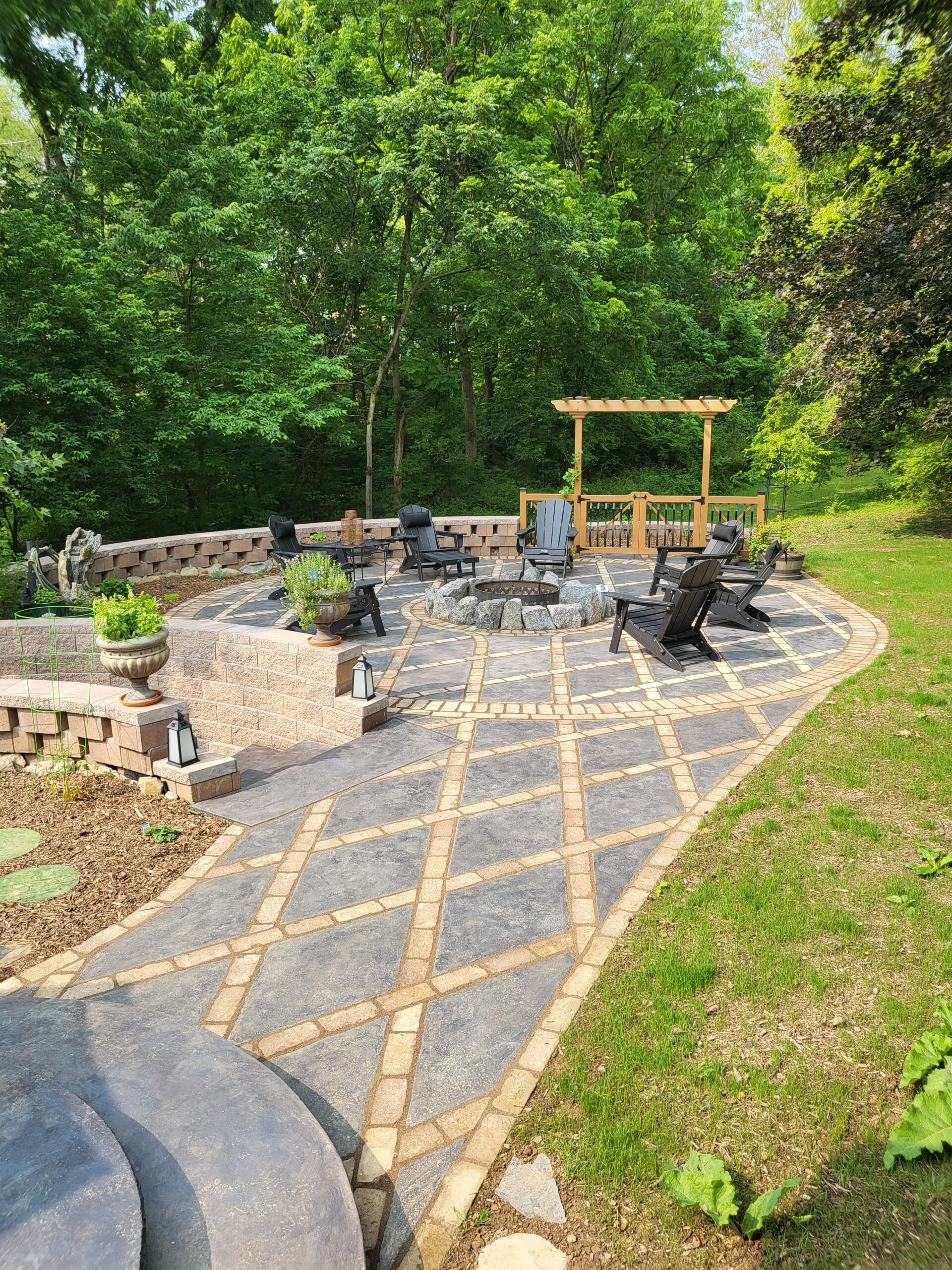 Fully transformed patio with light charcoal stained concrete diamonds, complemented by moss-inspired garden stepping stones