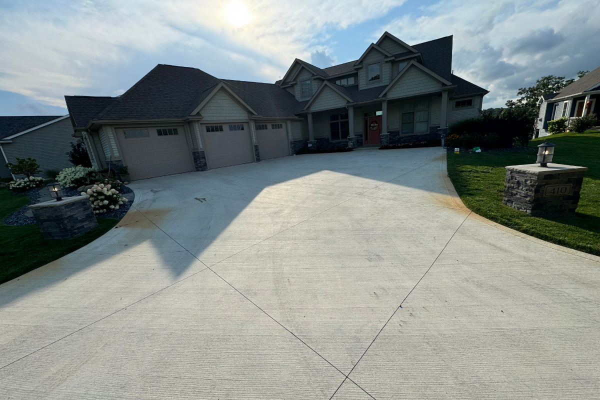 Before photo of broom-finished concrete driveway showing weathering, staining, and fading prior to staining.