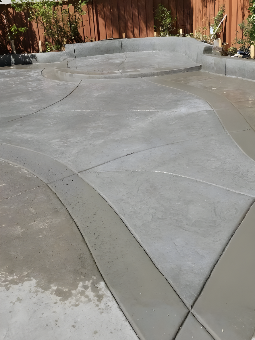 Backyard concrete patio showing uneven color between new and old concrete before staining