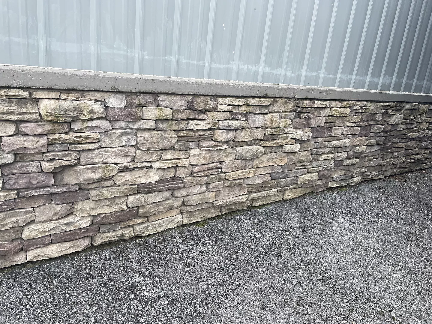 Faded stone veneer foundation before staining, showing dull and weathered tones