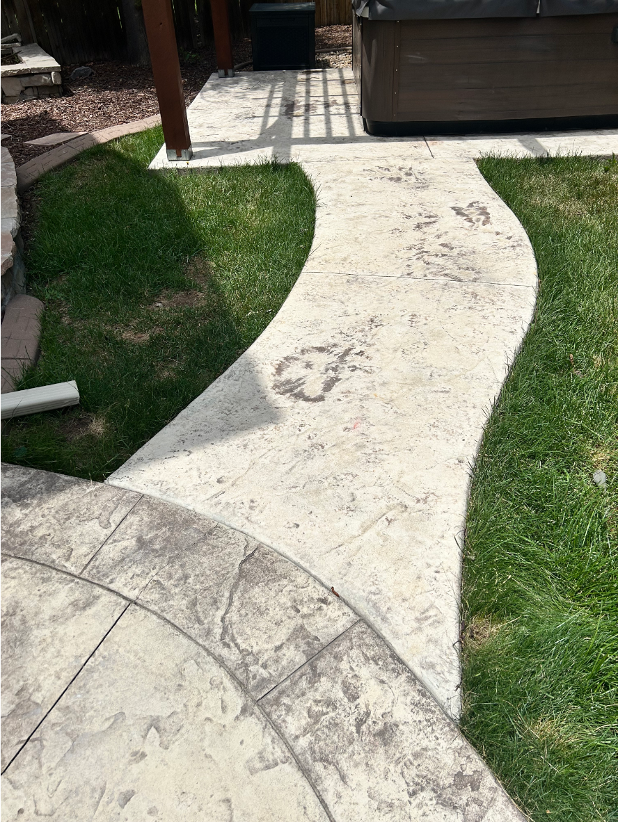 Faded, discolored stamped concrete patio and walkway before staining.