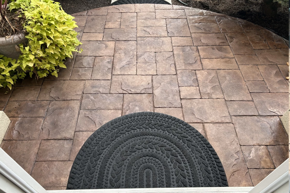 Restored stamped concrete front porch colored with Aztec Brown, Chocolate, Buff, and Cinnabar Antiquing™ Stains, sealed to a smooth satin finish.