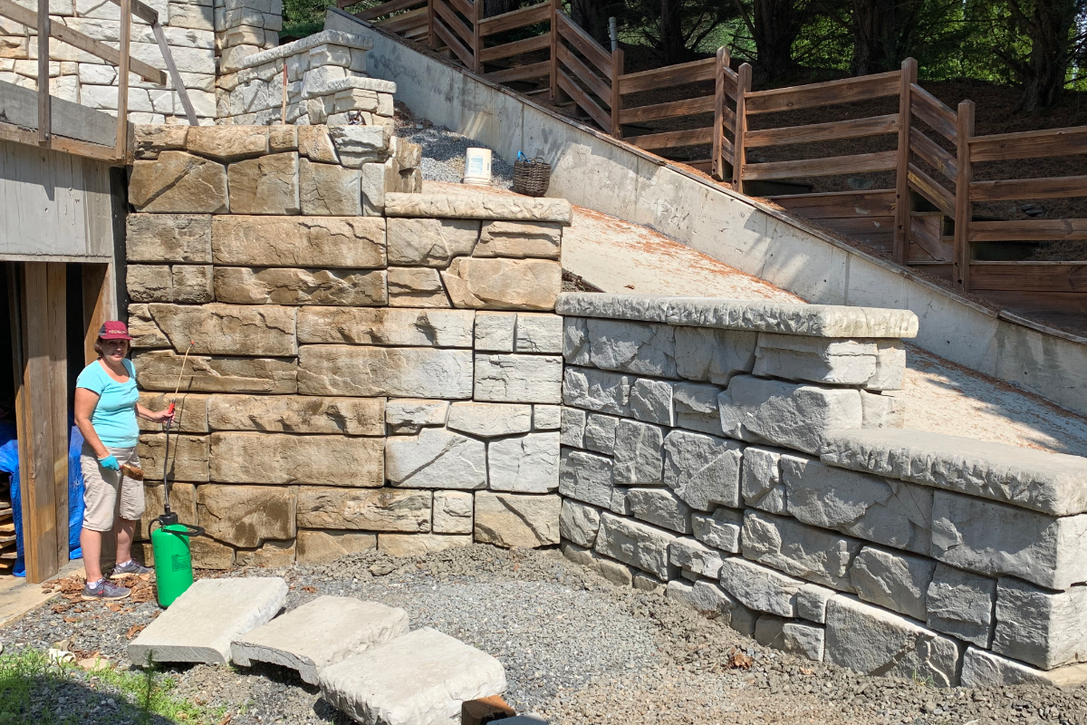 DIYer applying Cafe Royale EasyTint Tinted Sealer to a concrete wall using a good quality sprayer