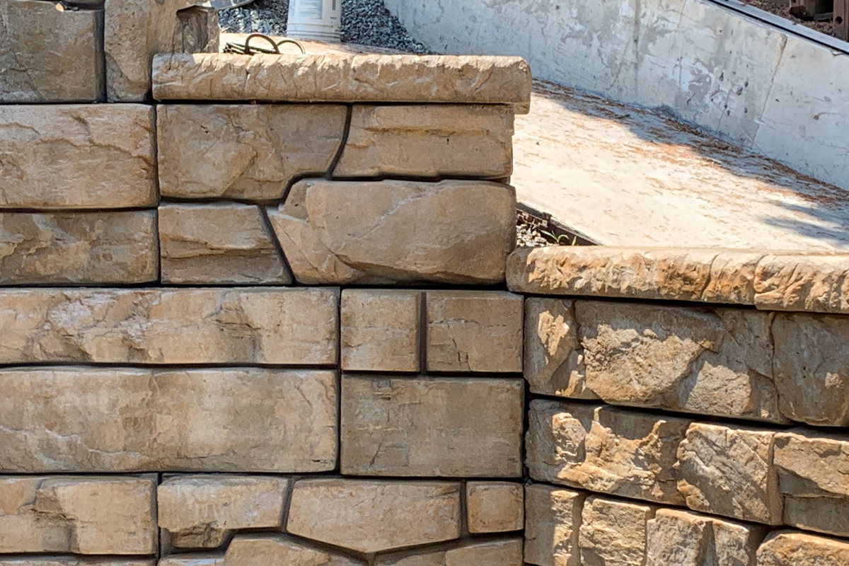 Retaining wall finished with Café Royale EasyTint™ Satin, showing rich brown tones and natural stone texture.