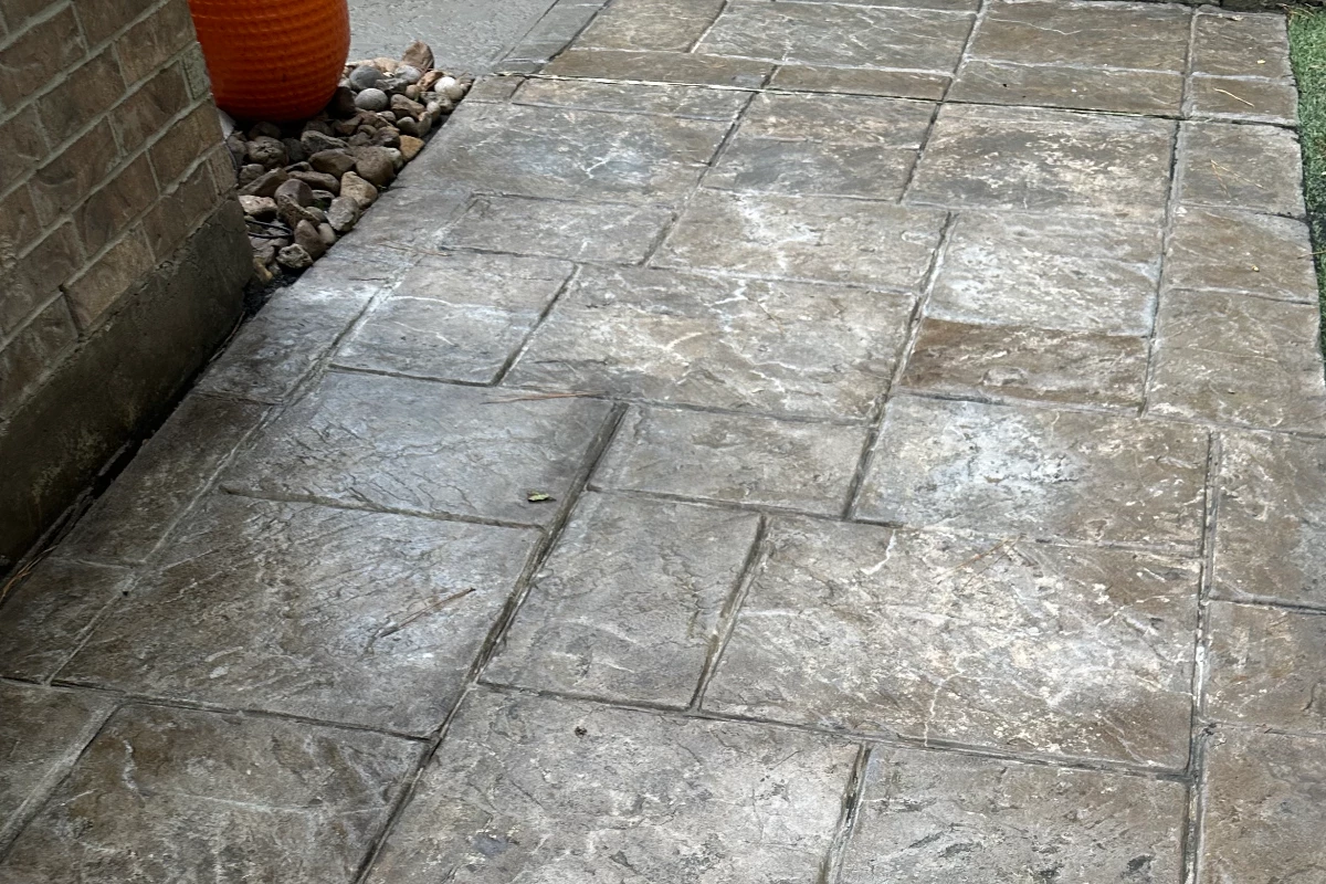 iscolored and faded stamped concrete, showing signs of wear and age.