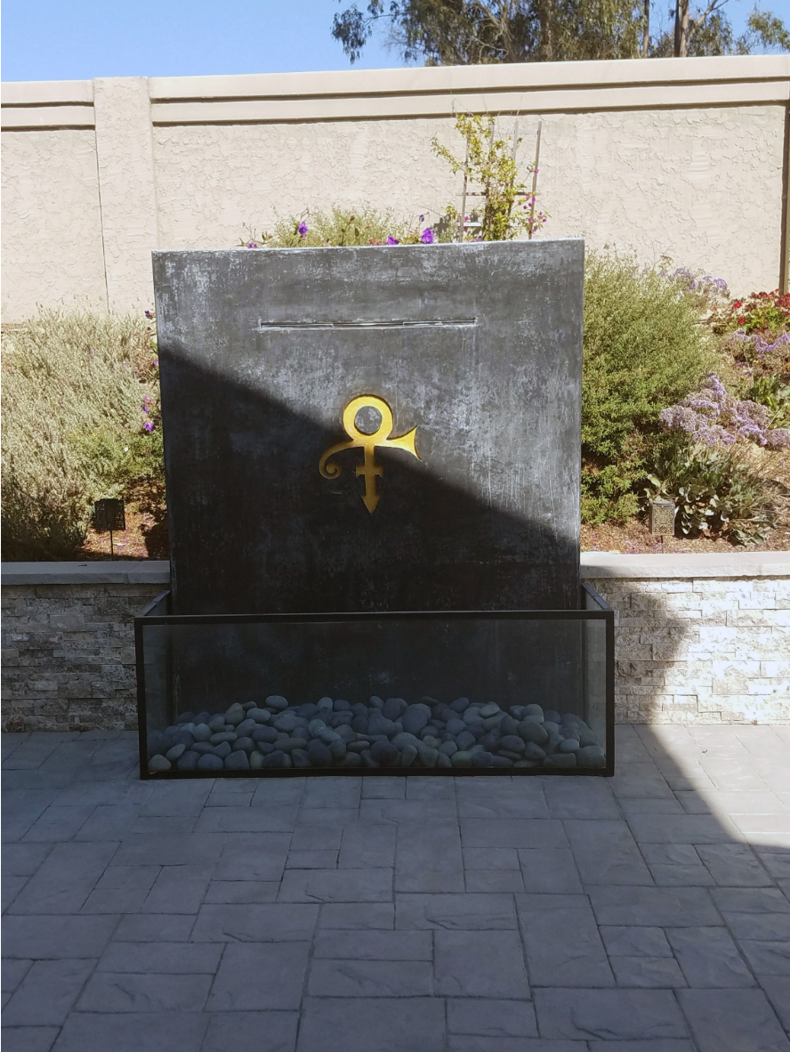 Before image showing a faded concrete monument dedicated to Prince, with his signature symbol engraved.