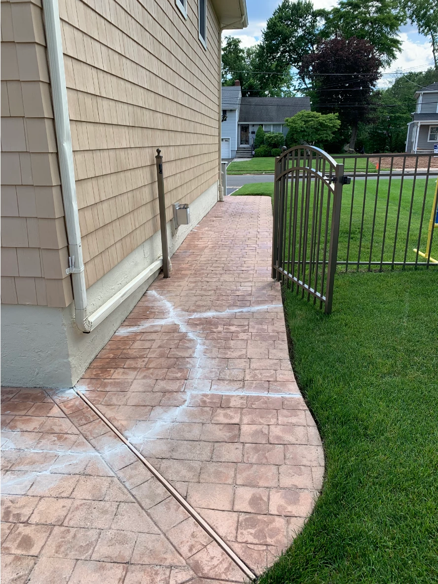 Before photo of stamped concrete patio showing prominent cracks and faded coloring prior to repair and staining.