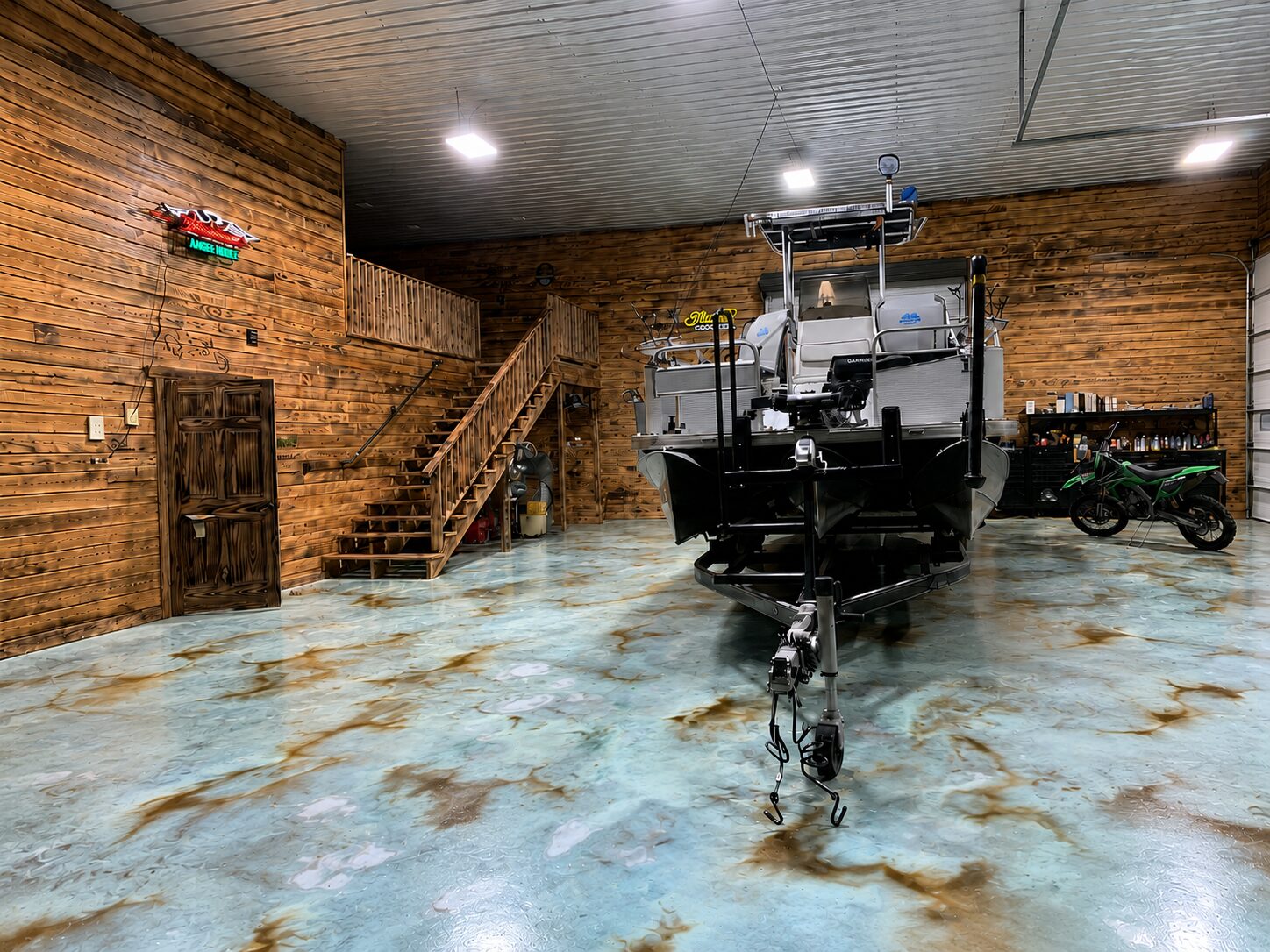 Boat storage garage with EverStain Azure Blue and Coffee Brown acid-stained concrete floor, showing a light blue-green marbled finish with warm brown accents.