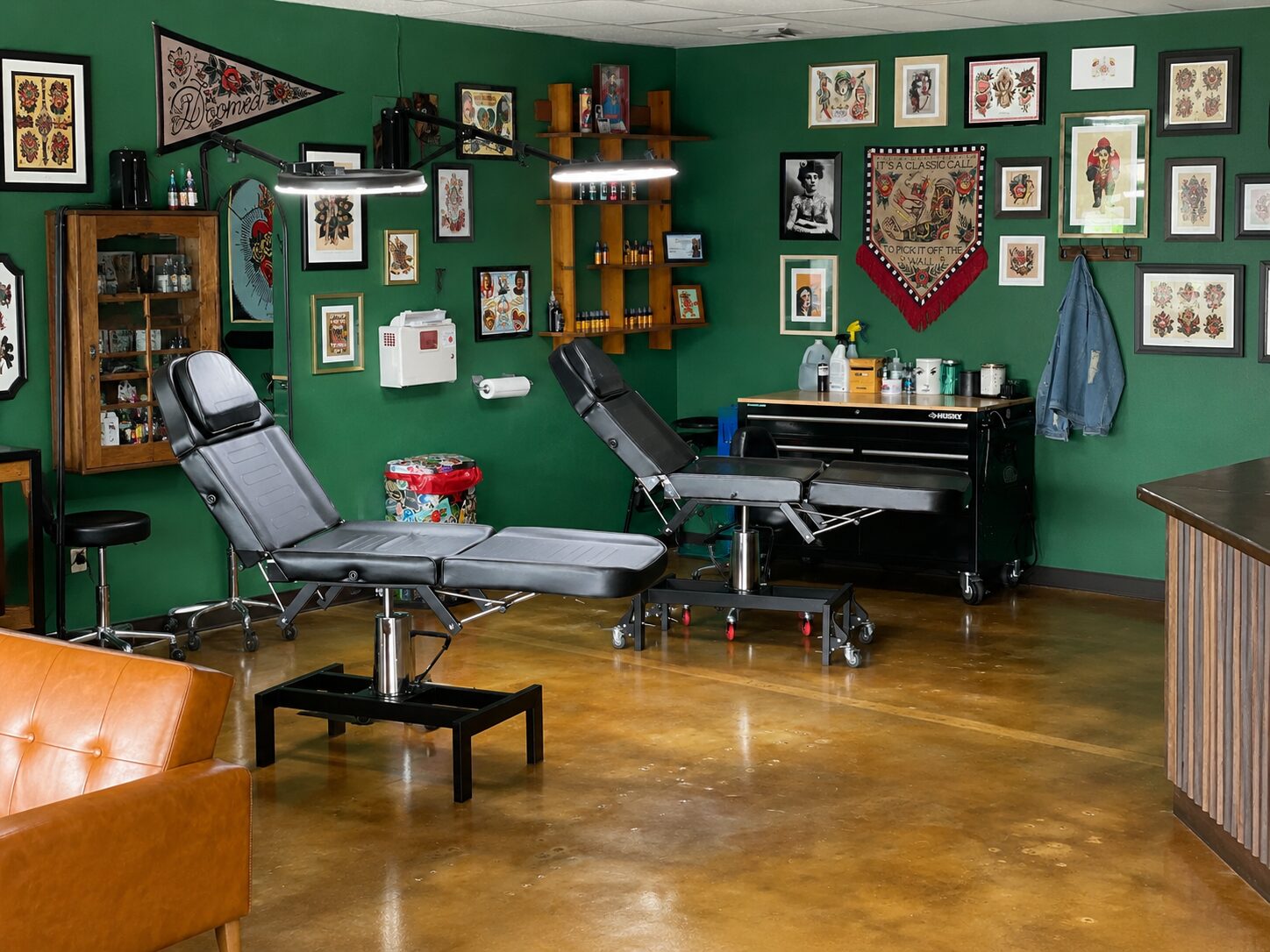 Tattoo studio with EverStain Malayan Buff and Shifting Sand acid-stained concrete floor, showing a warm polished finish with green walls and traditional tattoo artwork.
