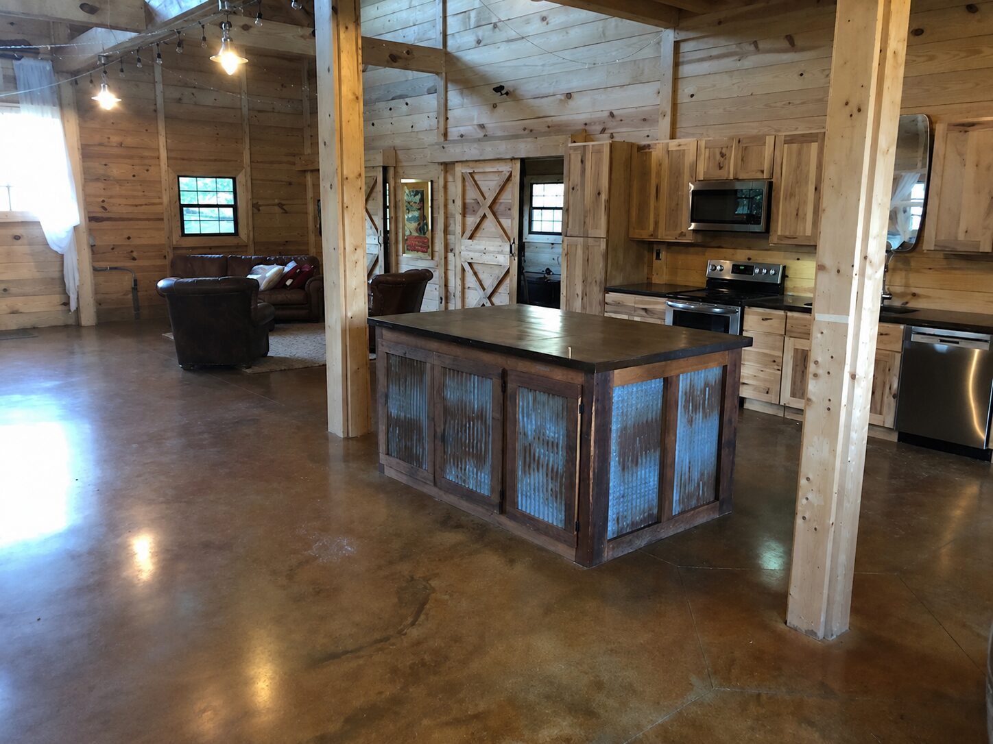 Rustic barndominium kitchen and living space with EverStain Shifting Sand and Malayan Buff acid-stained concrete floor, showing a warm polished brown finish.