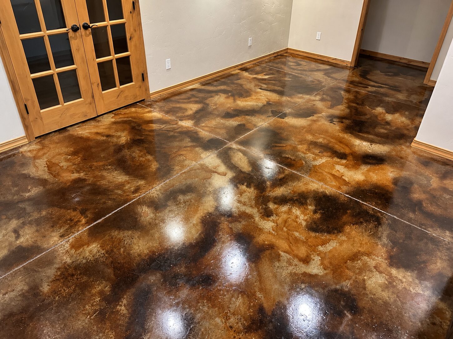 Residential interior with EverStain Malayan Buff, Desert Amber, and Coffee Brown acid-stained concrete floor, showing a glossy warm brown marbled finish.
