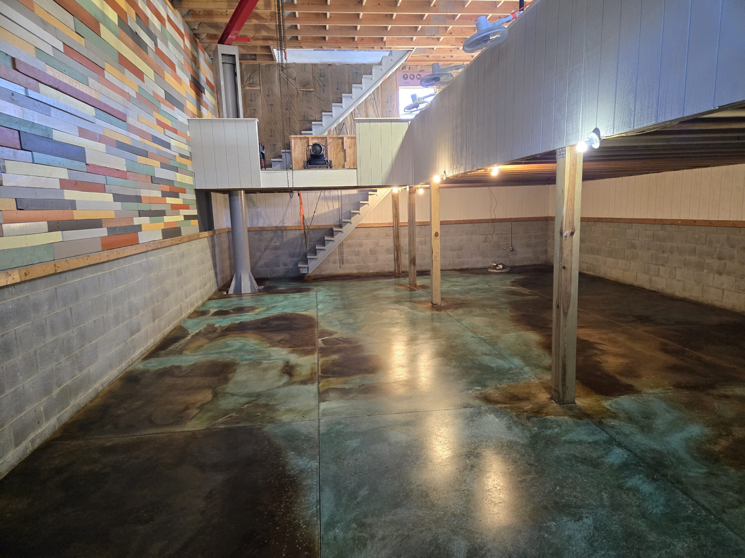 Studio concrete floor acid stained with EverStain Azure Blue, Black, Coffee Brown, Desert Amber, English Red, and Seagrass, with Miracle-Gro enhancing the blue-green marbled effect.