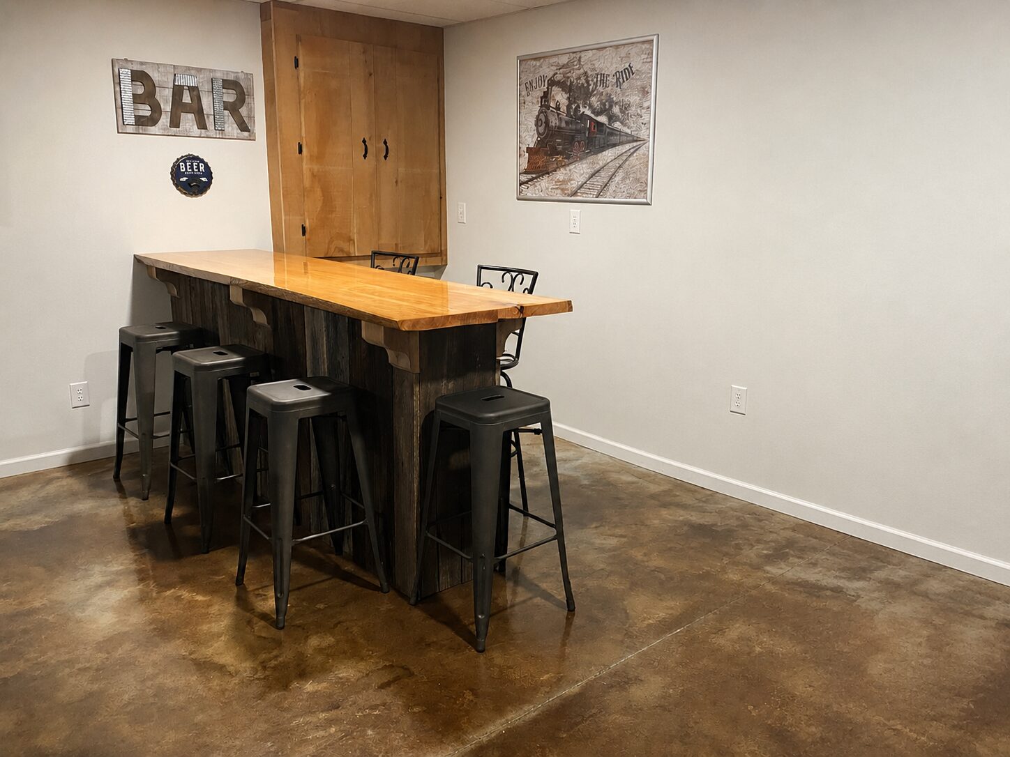 Basement bar with EverStain Coffee Brown and Desert Amber acid-stained concrete floor, showing a warm brown marbled finish around a rustic wood bar.
