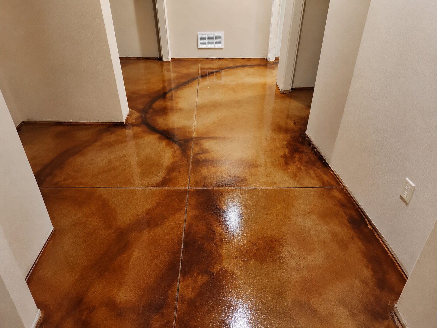 Residential hallway with EverStain Coffee Brown and Malayan Buff acid-stained concrete floor, showing a glossy warm brown marbled finish.